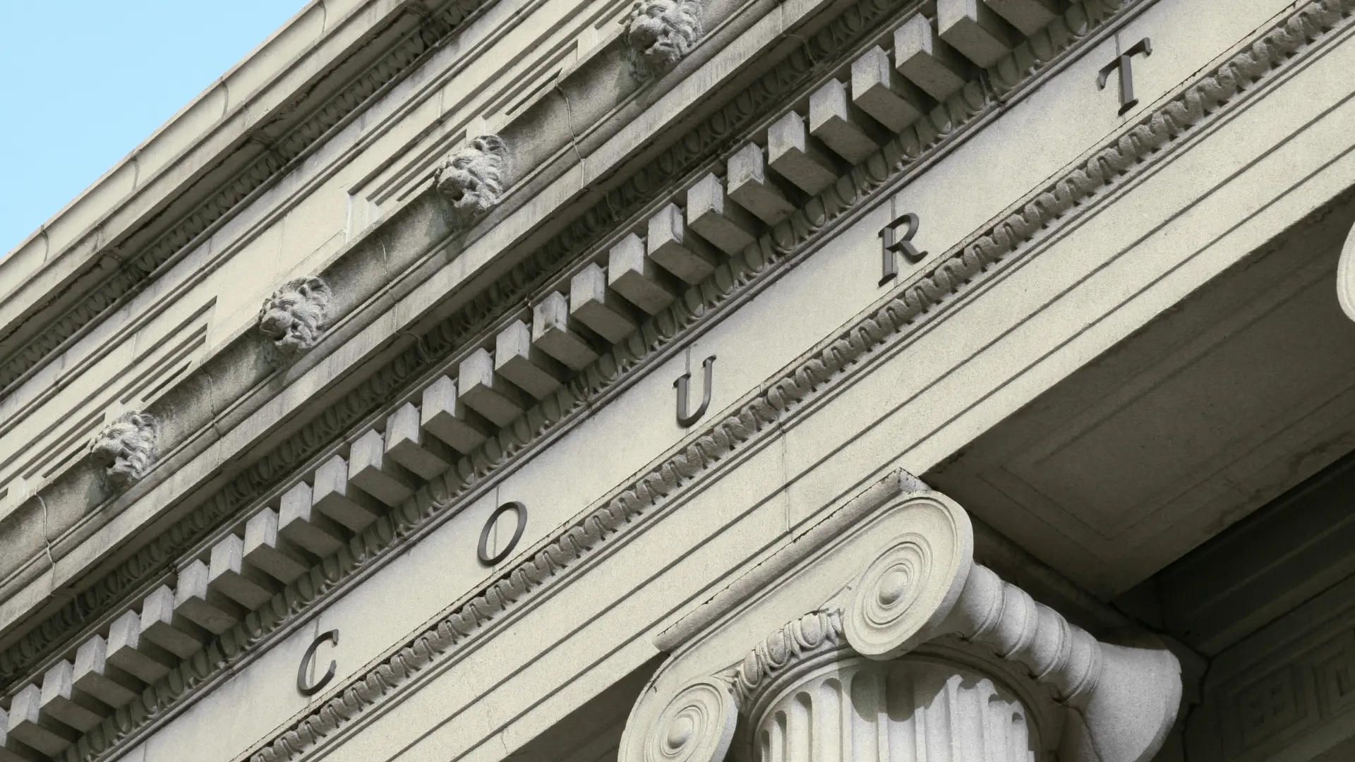 Close-up architectural detail of a courthouse exterior with carved columns and the word “COURT” engraved.