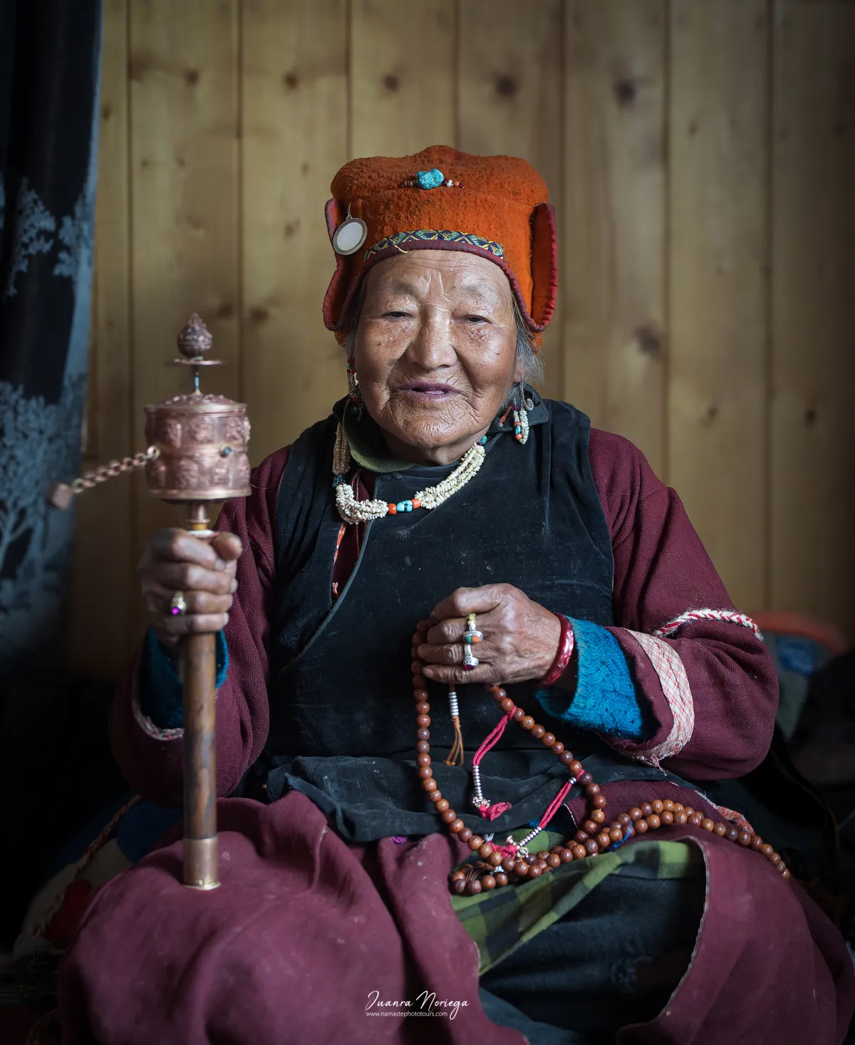 Anciana sonriente con molinillo de oración y rosario budista, en Ladakh