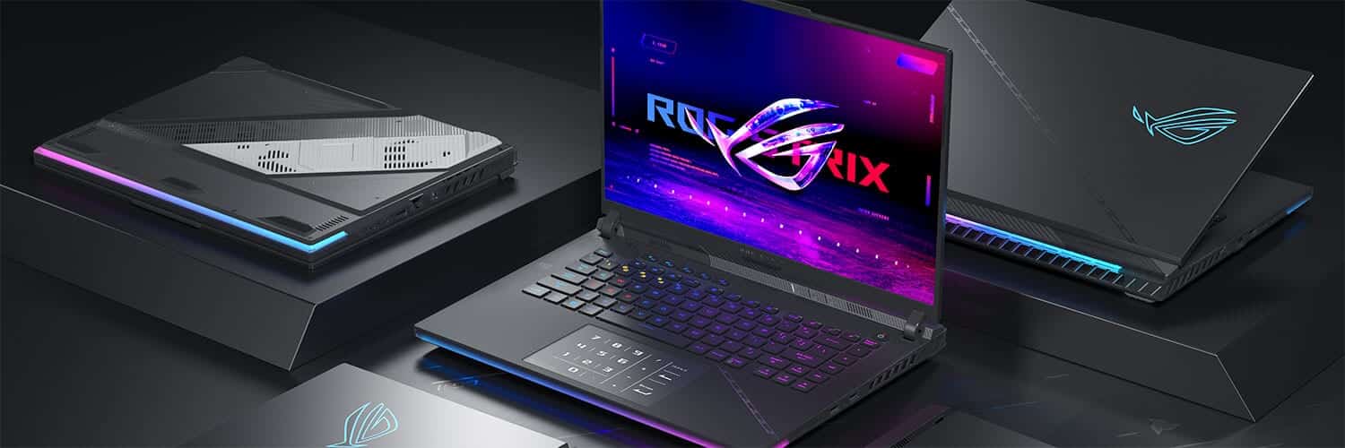 Asus ROG Strix SCAR 18 gaming-laptop i aggressivt sort design med RGB-lys og stor skærm, flankeret af flere enheder i et stilrent gamer-setup.