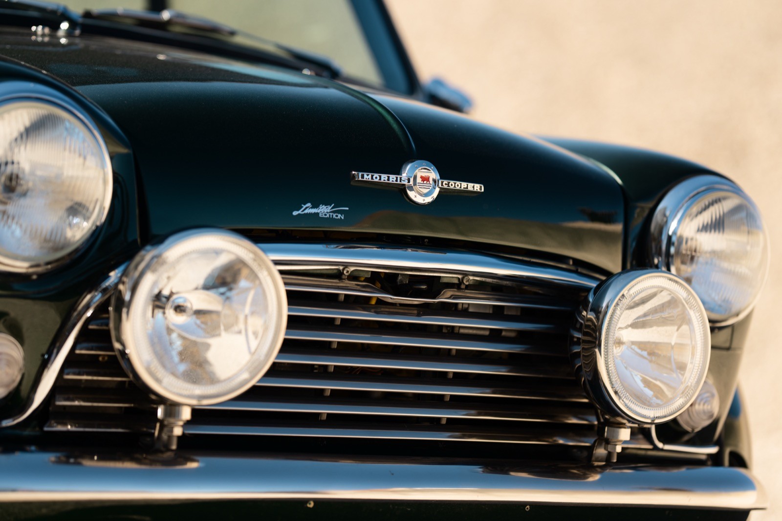 A small, green and black vehicle parked on a sandy surface, with a warm sunset lighting the scene.