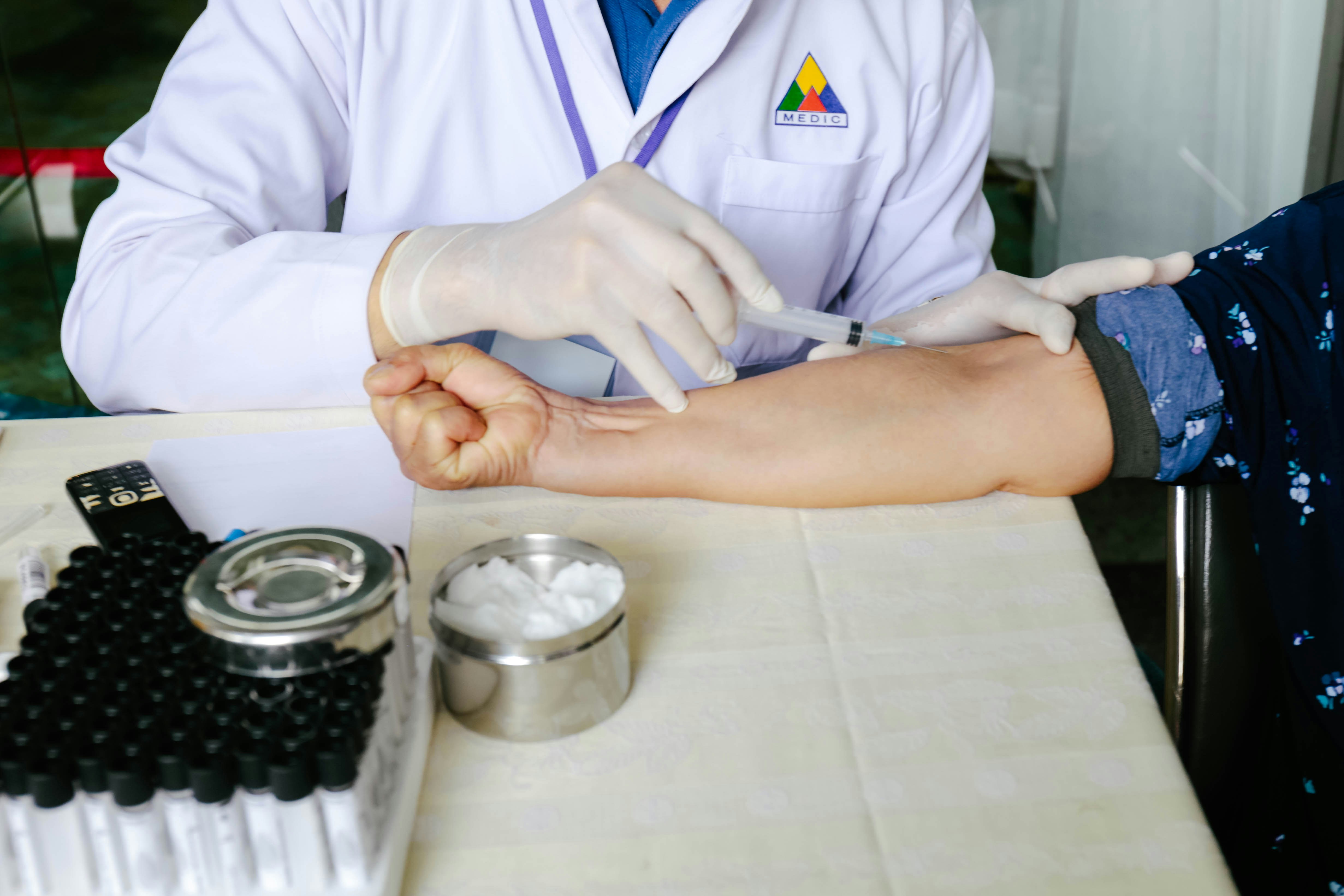 A doctor's hand in gloves, giving an injection to a patient