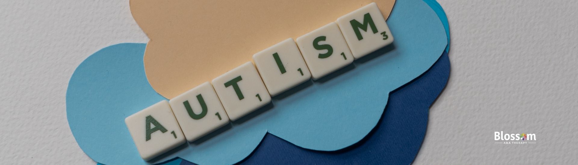 The word Autism spelled using Scrabbles with cloud background.