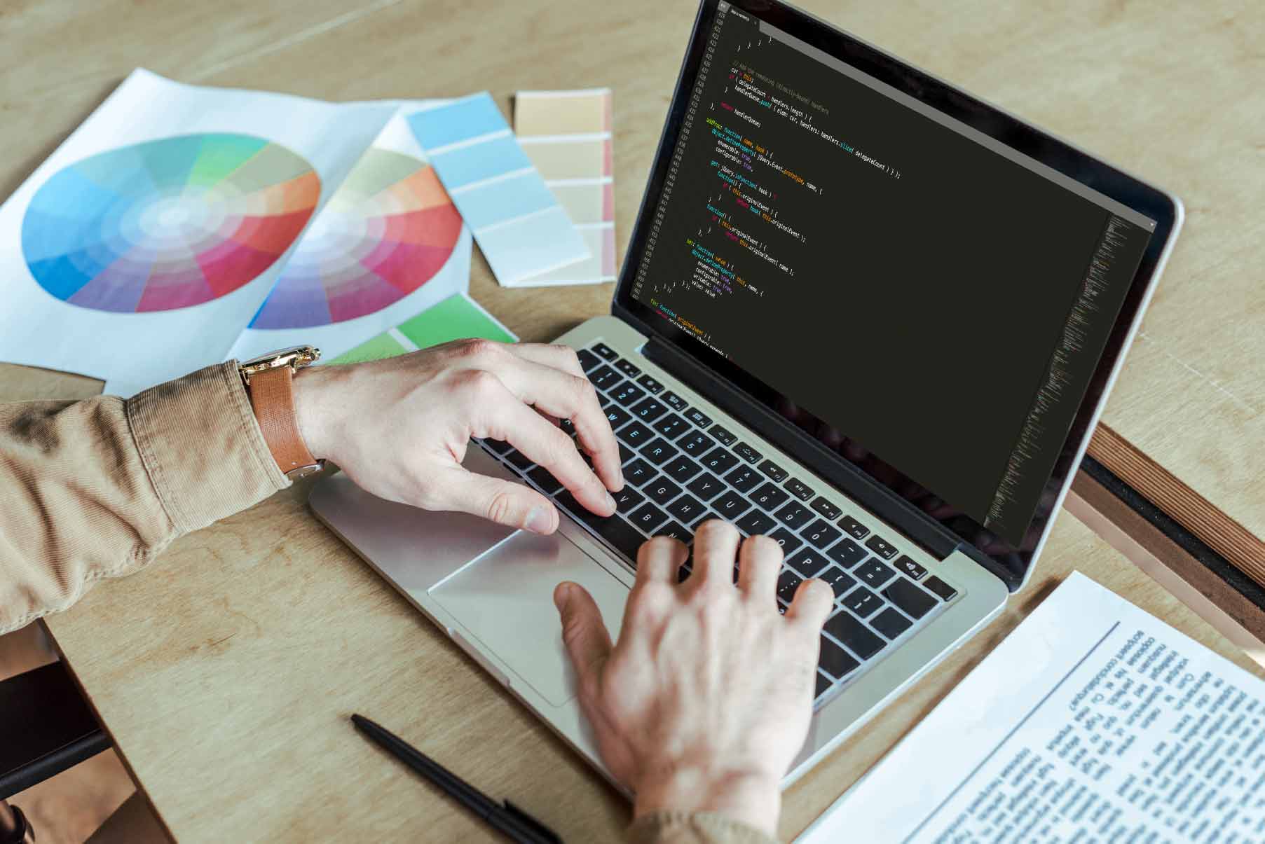 Specjalista spójnia studio zajmujący się web developmentem koduje nową stronę internetową na laptopie, dopasowując palety barw do nowoczesnego web designu.