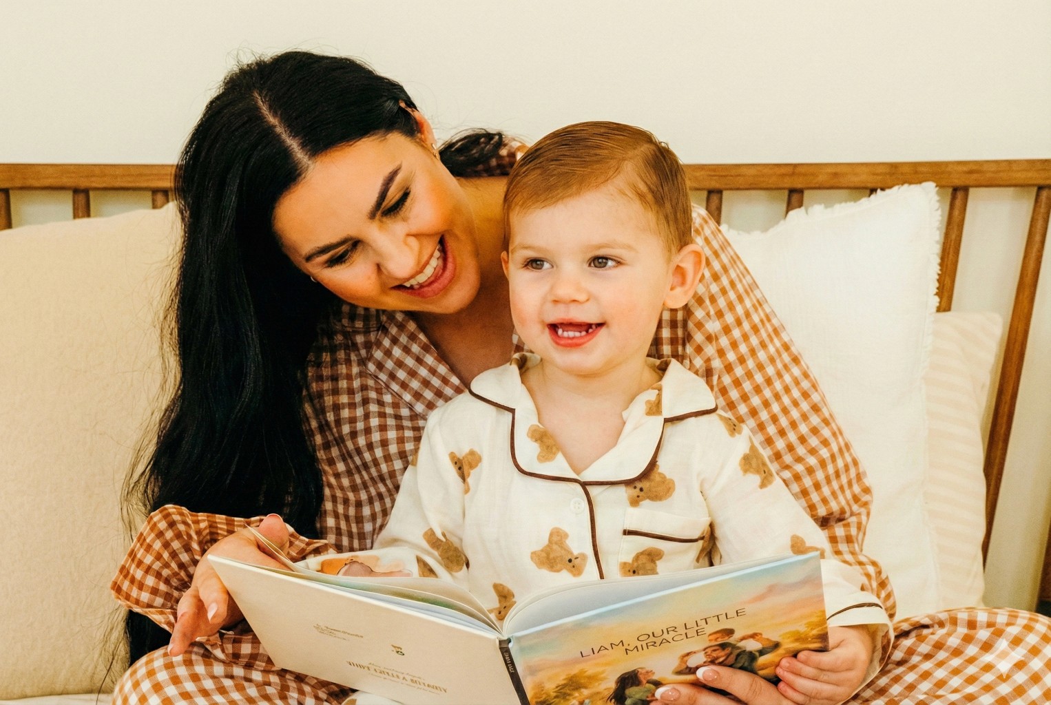 A smiling young man with crossed arms, wearing a plaid shirt and white t-shirt, poses against a dark background.