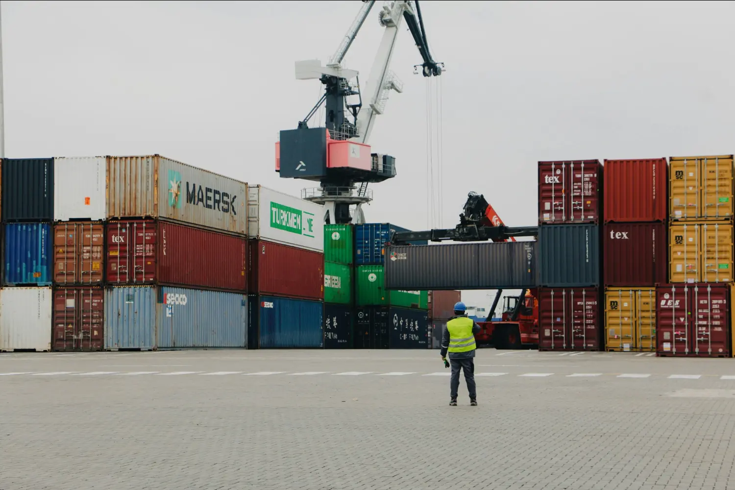 Containerumschlag im Hafen während der Zollabfertigung in Deutschland mit Frachtcontainern und Verladekran.