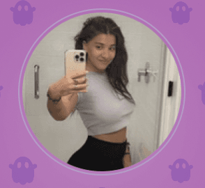 Moody portrait of a woman with straight dark hair and bangs leaning against a turquoise and pink wall, illuminated by soft natural light.