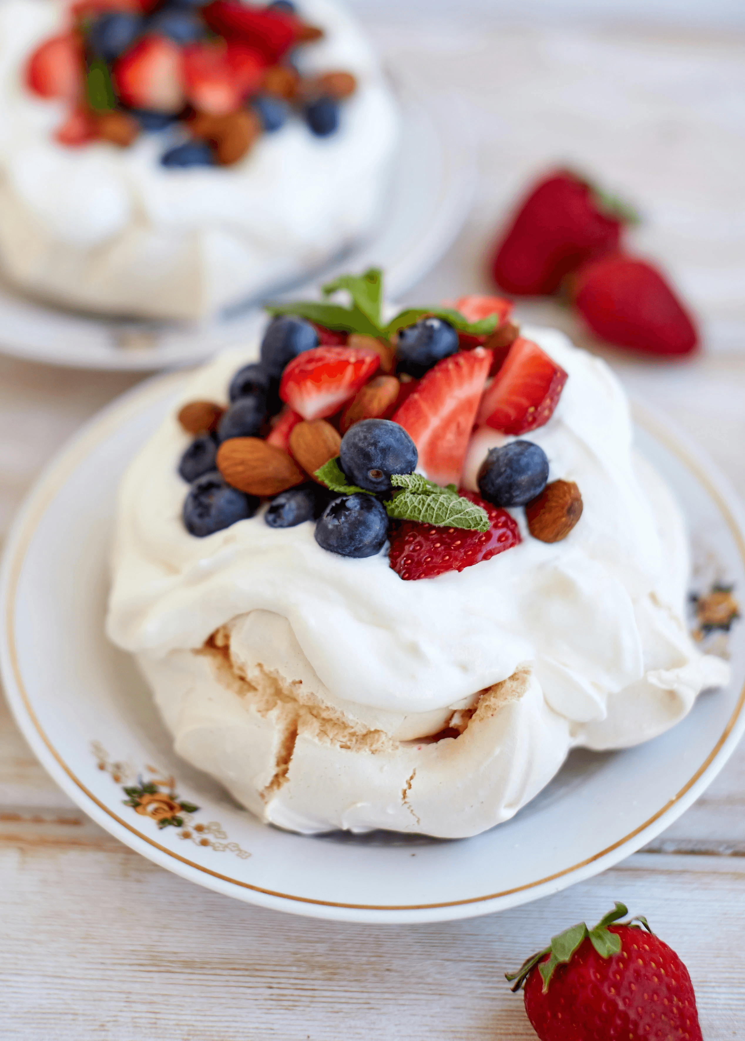 two desserts on a white plate with strawberries and blueberries