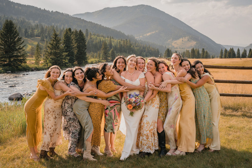 Bride surrounded by her wedding party in a mountain meadow