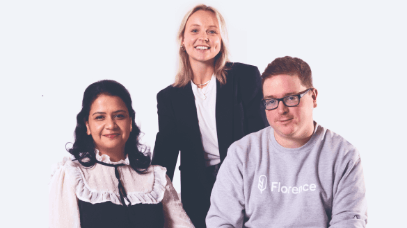 Three team members smiling in a studio-style group portrait against a plain background.