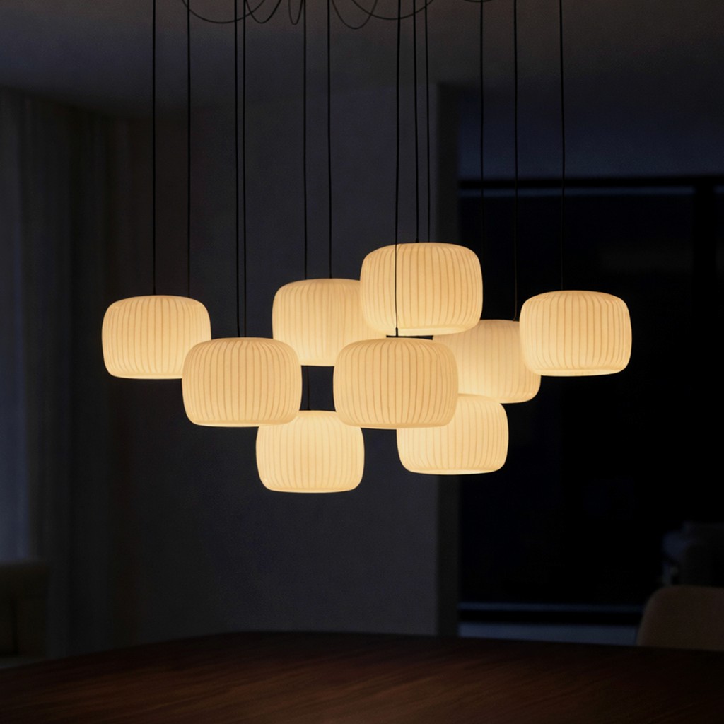 A close-up of a modern chandelier featuring a cluster of eleven glowing, ribbed lantern-style pendant lights hanging at varying heights.