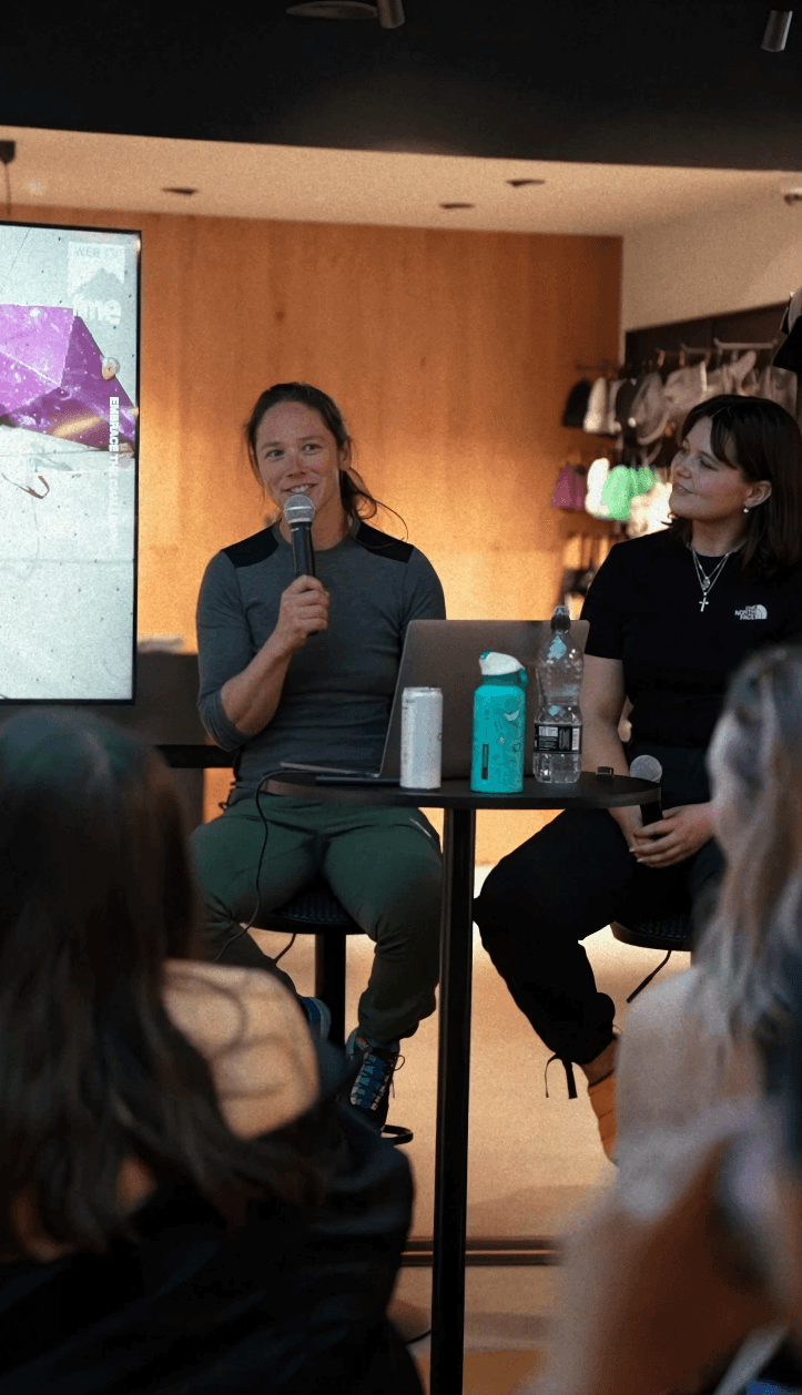 Bride sitting on ground against wall, groom standing nearby