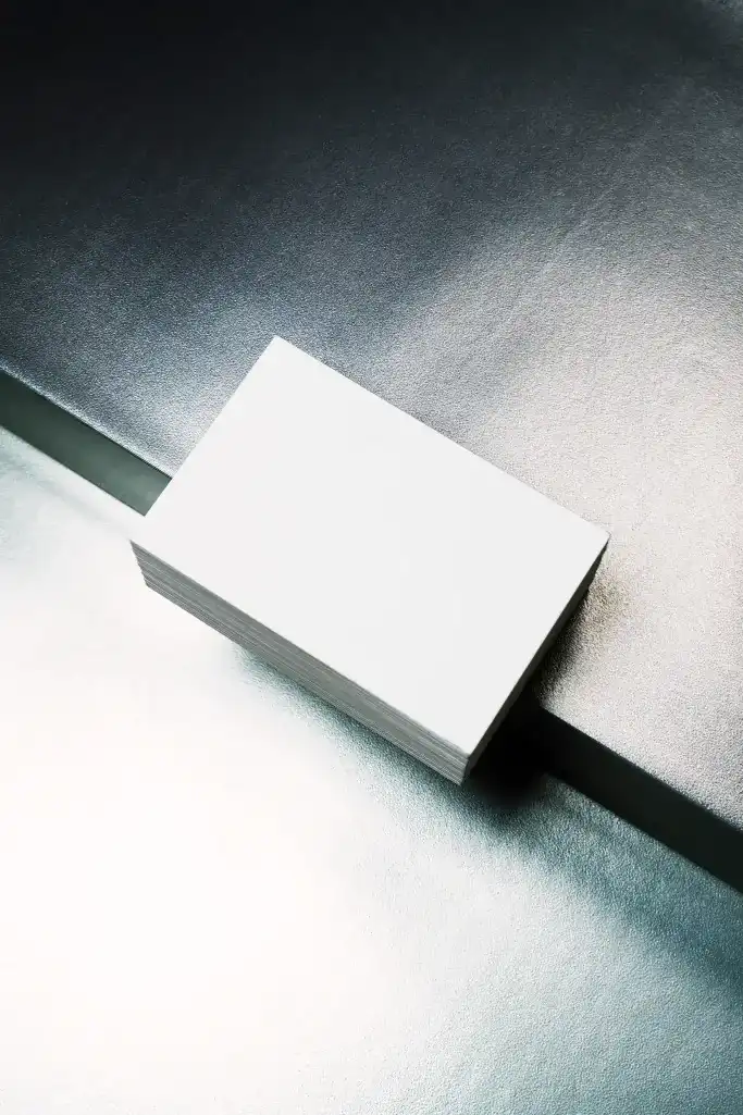 tack of modern business cards with a minimalist design, featuring bold black typography, bright green accents, and a gray background. Displayed on a metallic surface with dramatic lighting.