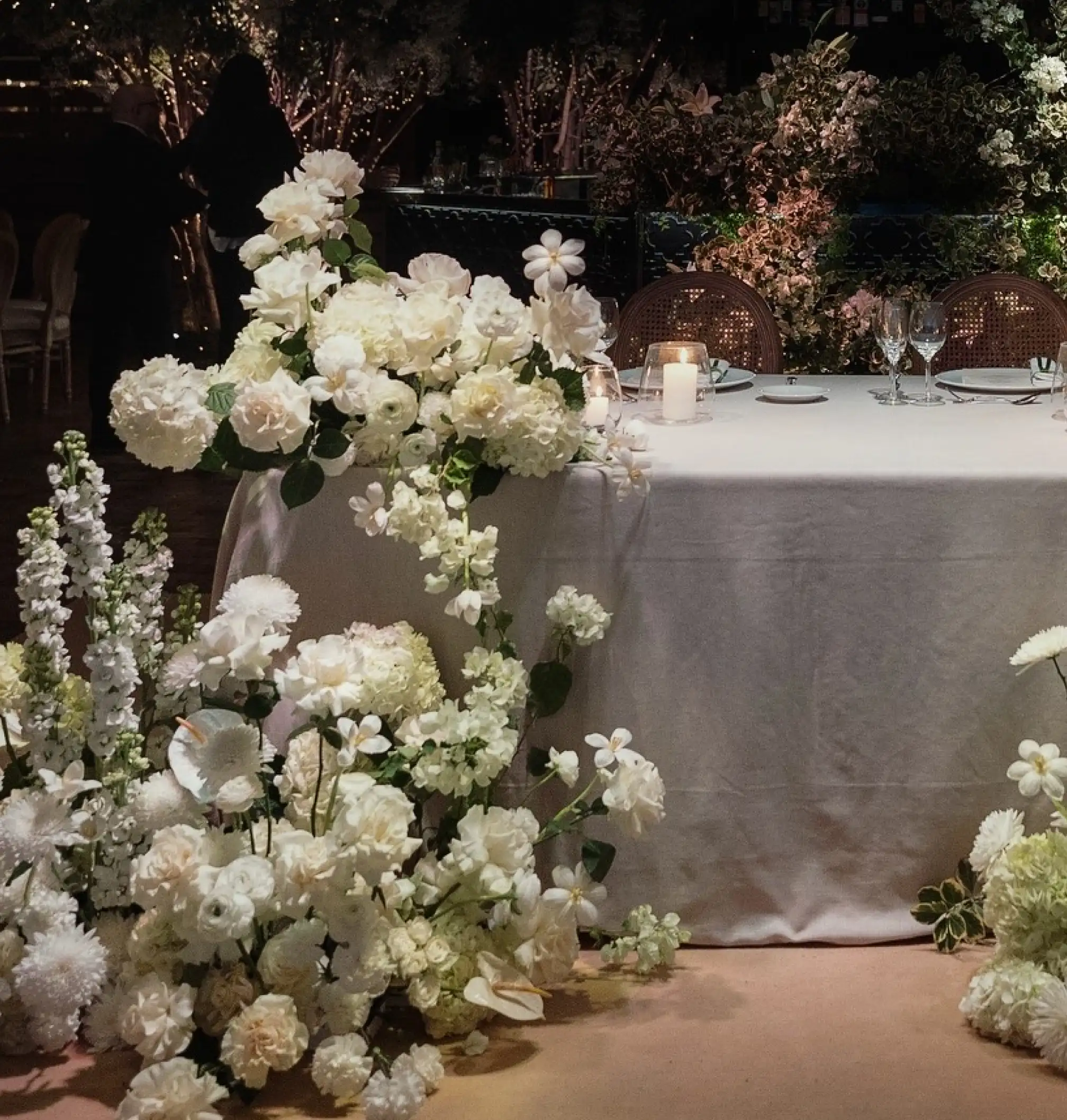 Mesa elegante decorada con flores blancas en cascada y velas, creando una atmósfera romántica y sofisticada.