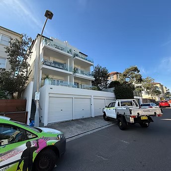 Hitech Remedial Group service vehicles parked outside a modern multi-storey residential apartment building in Sydney