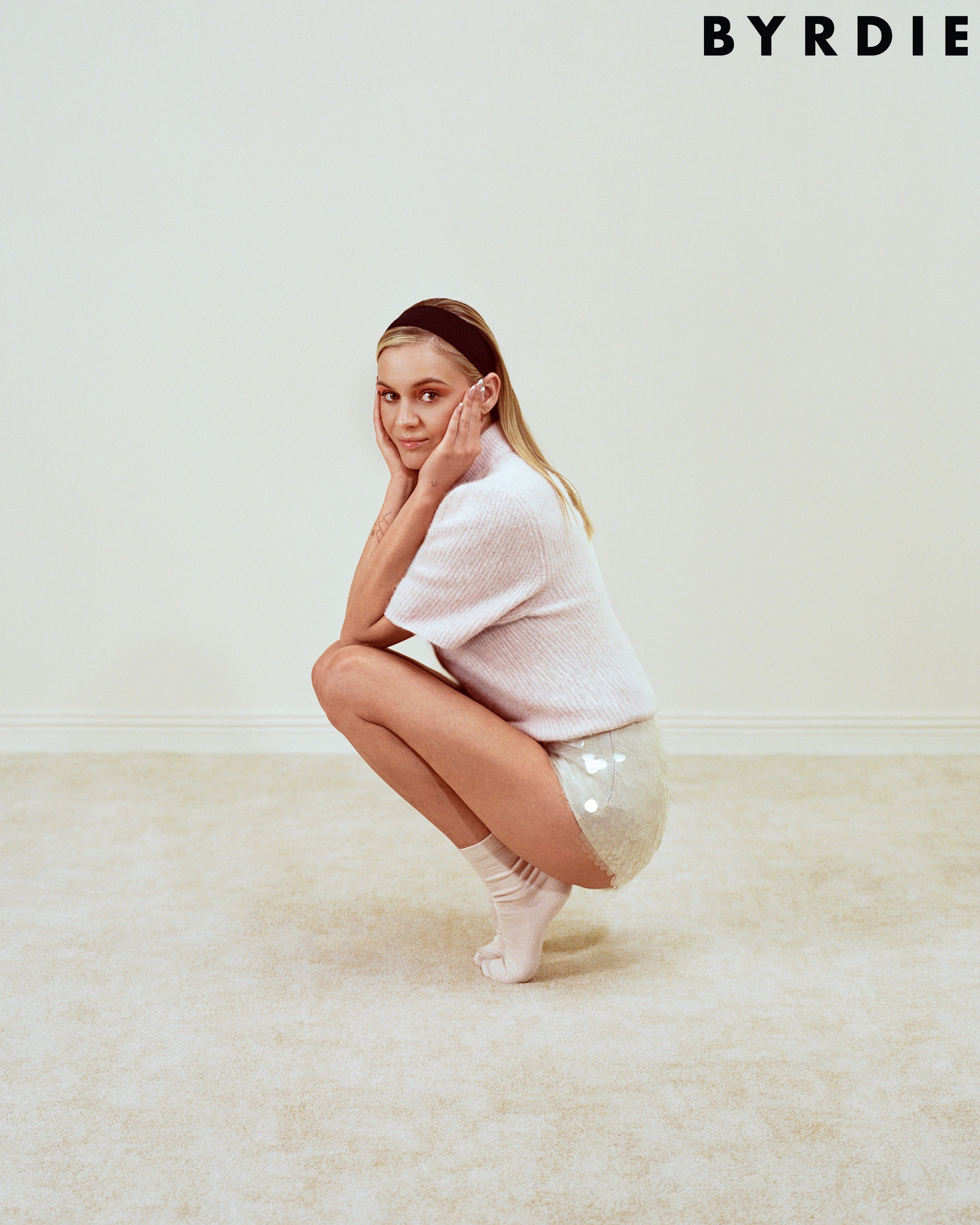 Kelsea Ballerini reclining on white carpet