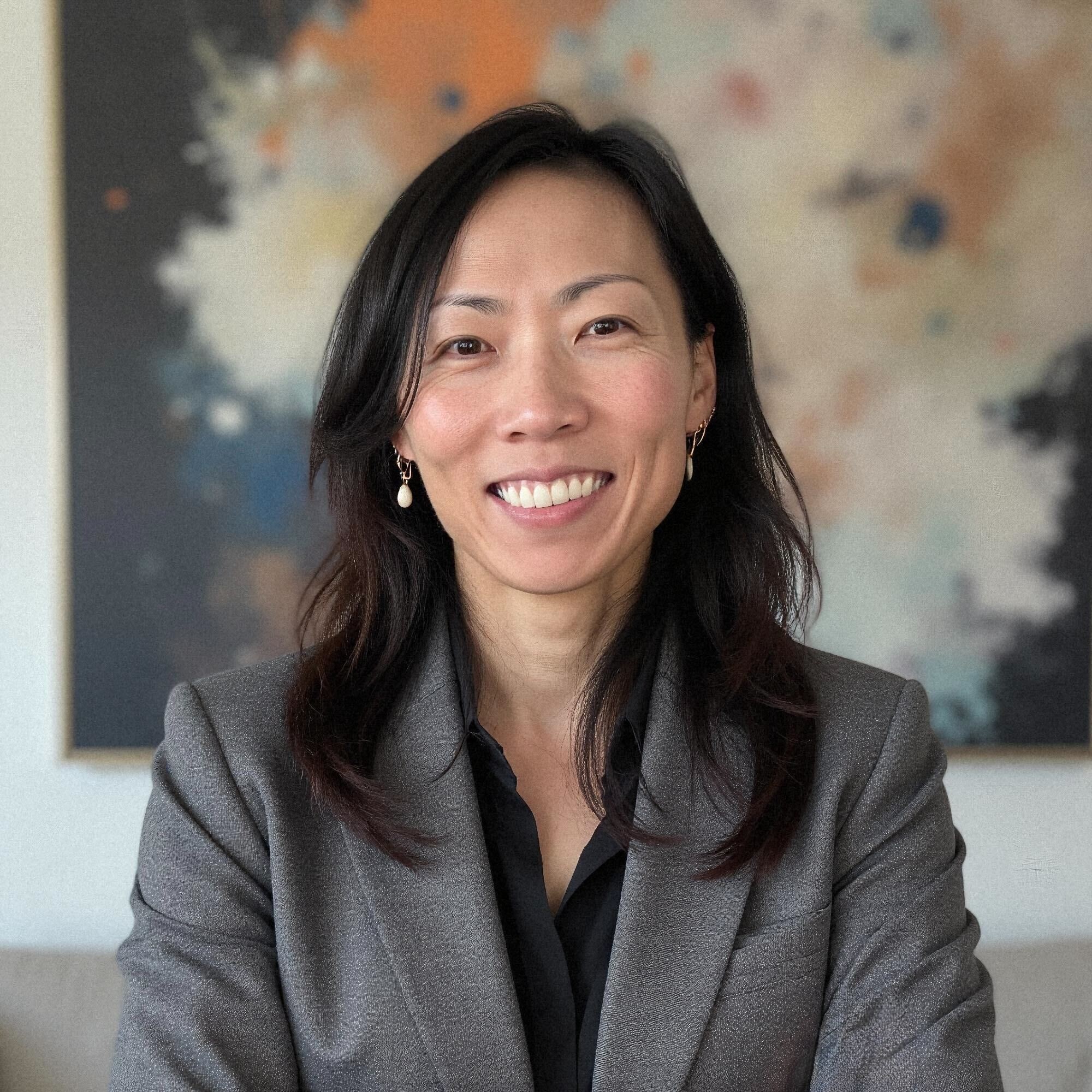 Portrait of comedian Ragnar Ísleifur Bragason smiling in a red blazer and glasses, framed by a rustic wooden beams and brick. 