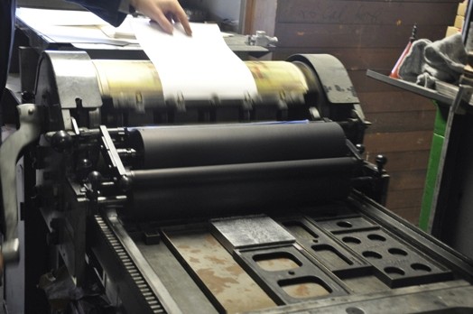 A photo of a paper put trough a printing press.