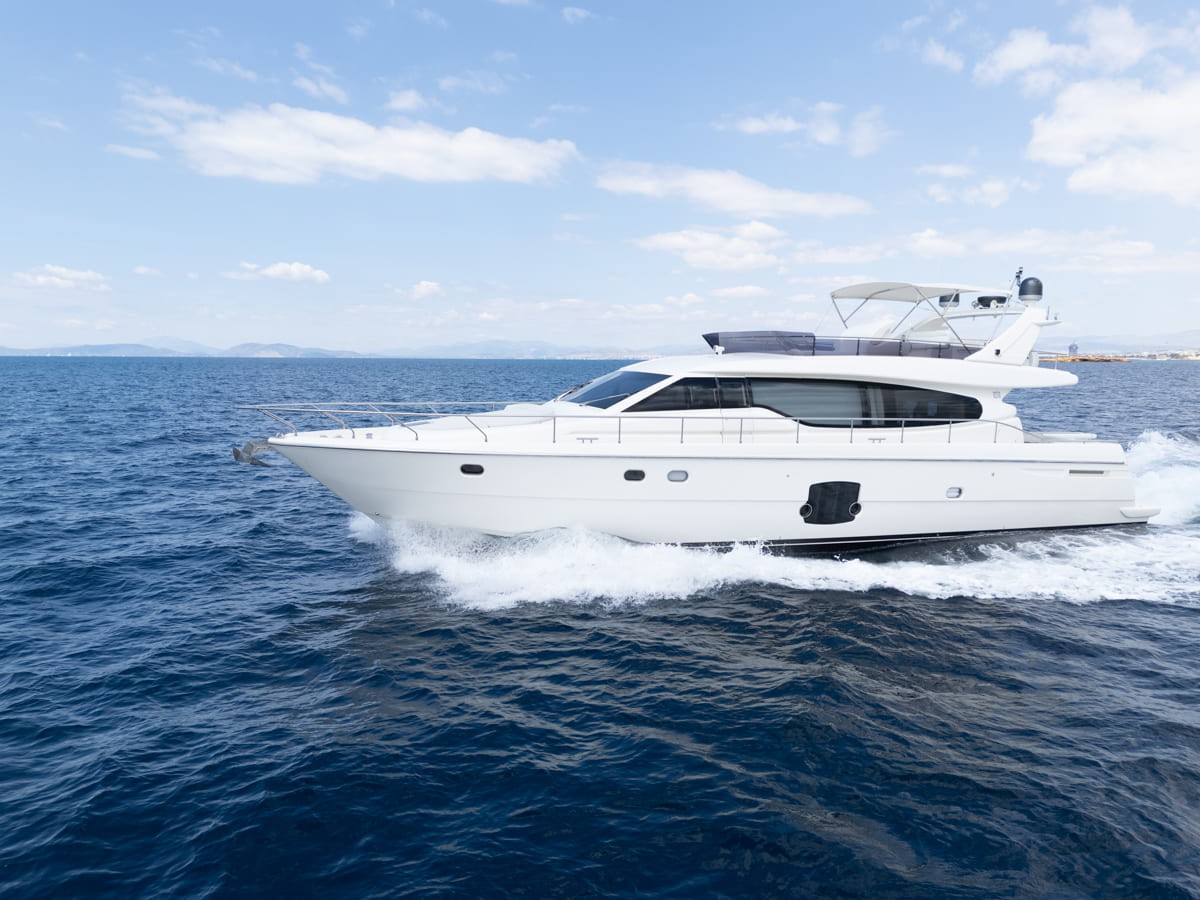 White Ferretti 63 motor yacht speeding through deep blue waters, creating dramatic white wake spray around the hull.