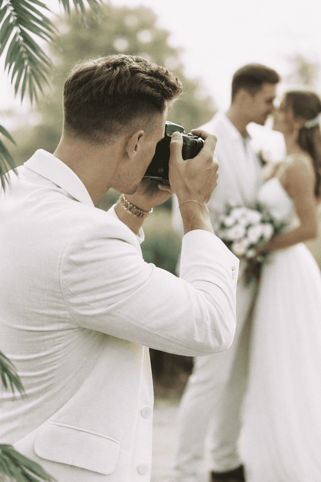 A couple in wedding attire shares a romantic moment as a photographer captures the scene.