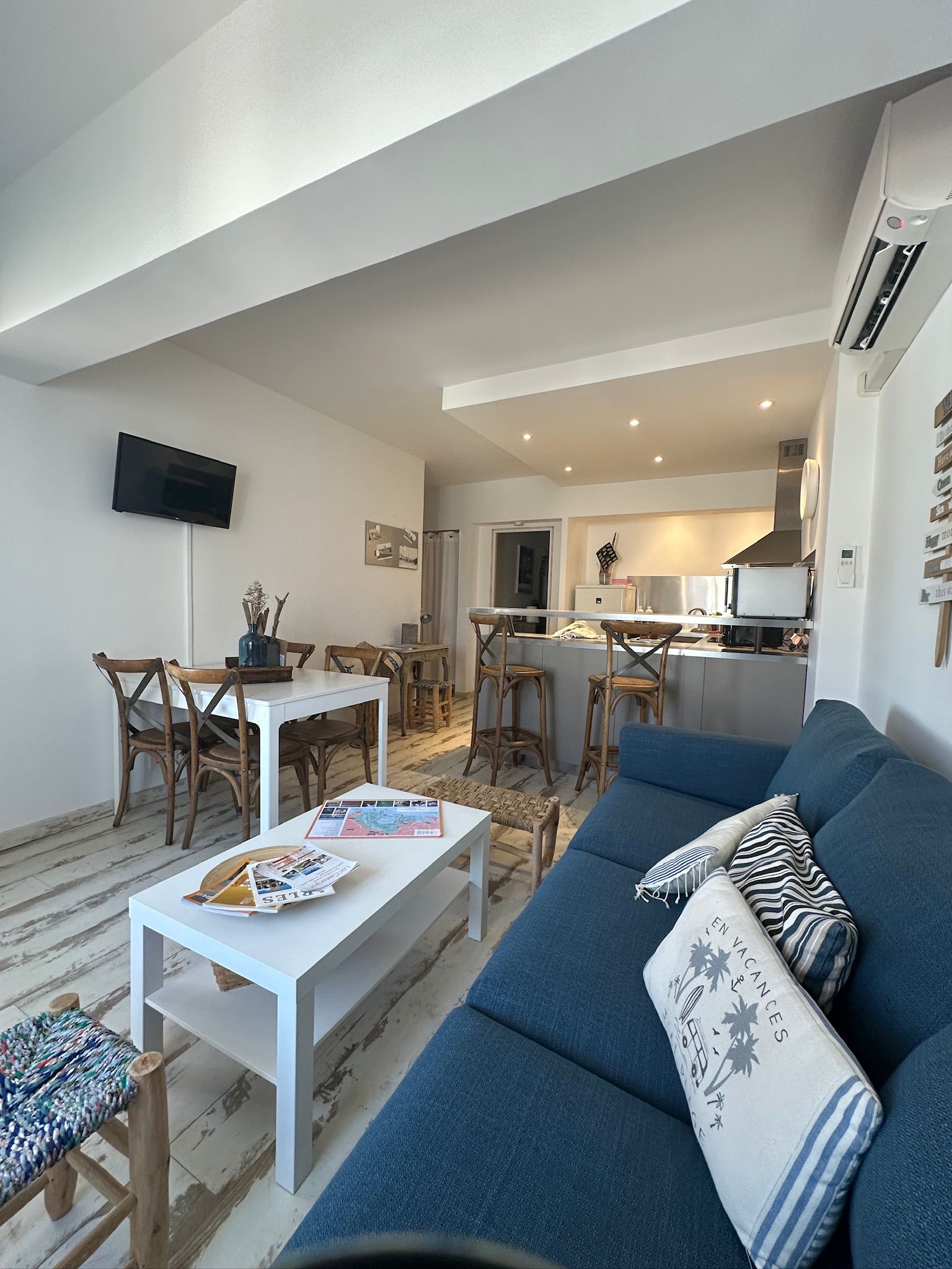 Décoration salon scandinave et bohème avec canapé gris, table basse en bois et cannage, et plantes vertes.