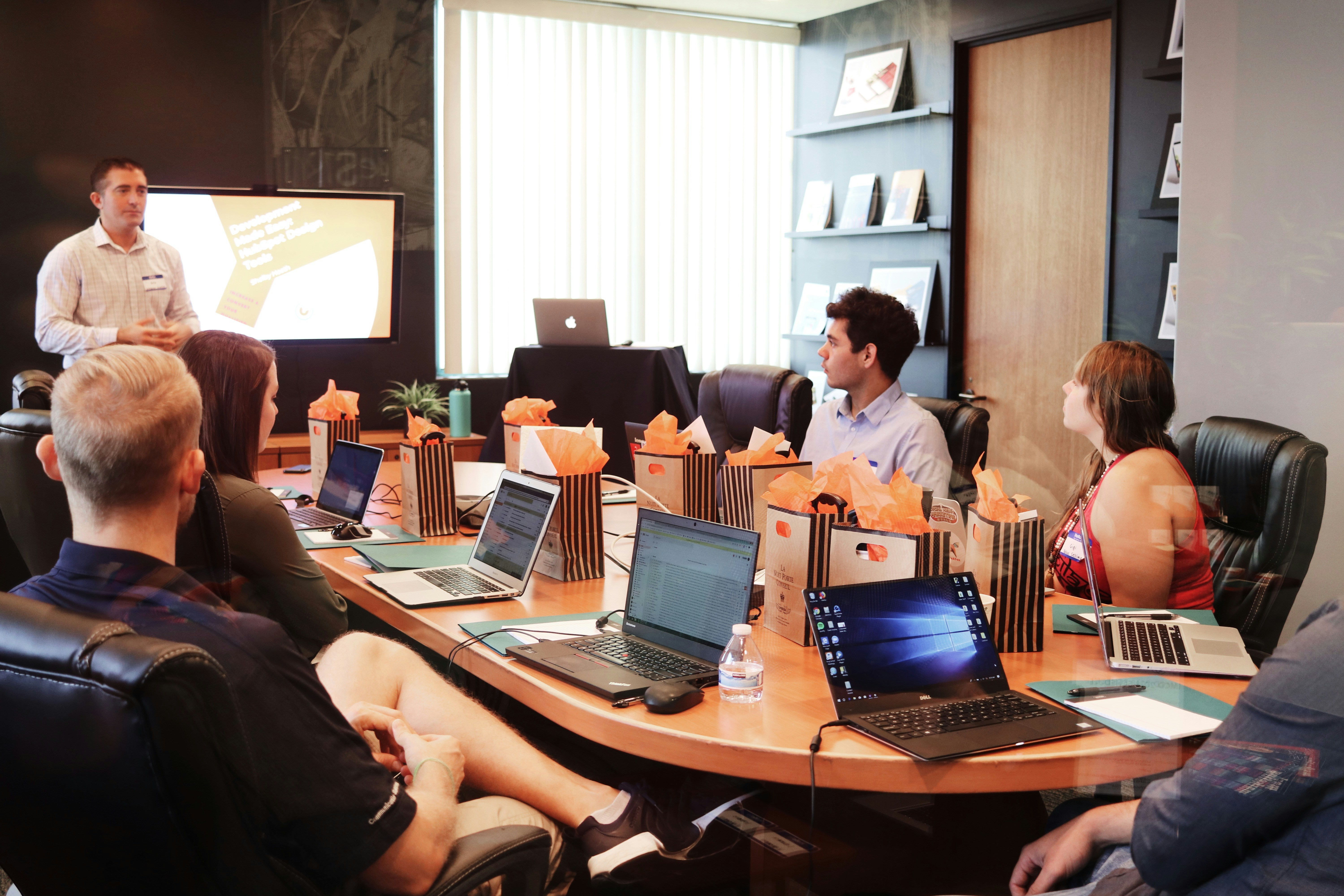 People having a meeting in the conference room with their laptops open.