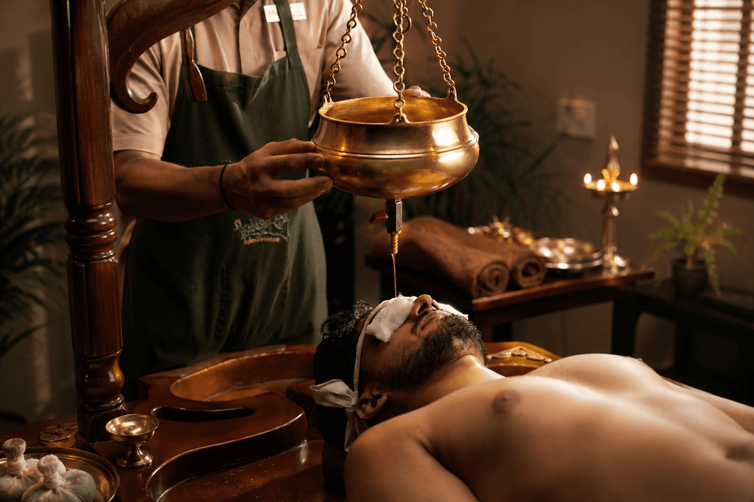 A person lying peacefully during a Shirodhara treatment at Au Revoir, with warm herbal oil flowing gently onto their forehead in a calm and serene Ayurvedic therapy setting.