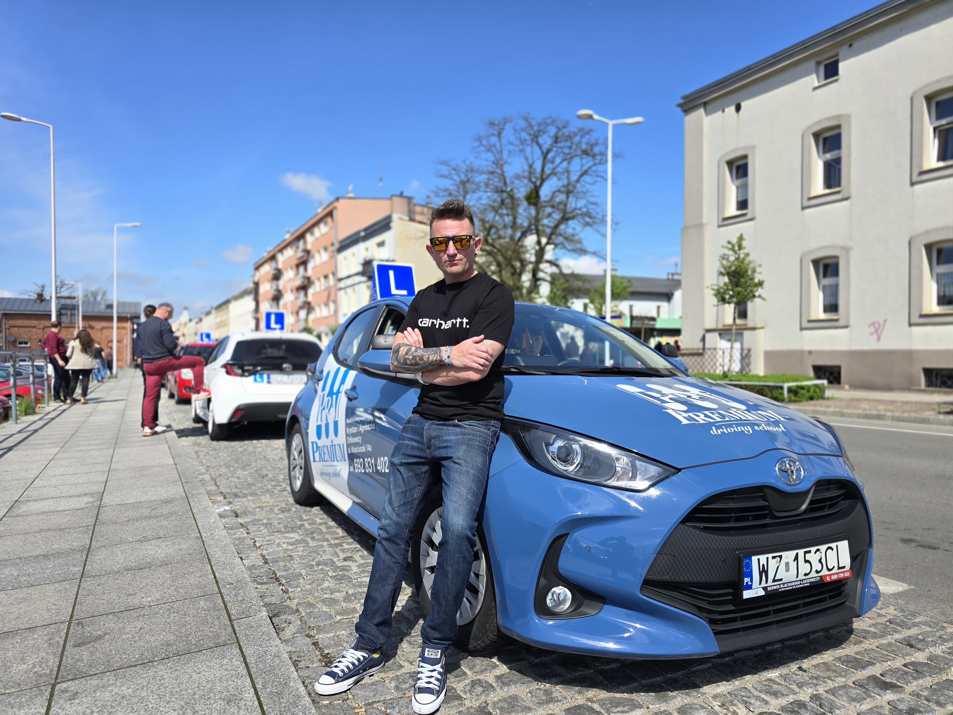 Łukasz Poraj – Instruktor stojący przy niebieskiej Toyocie Yaris oznaczonej literą L.