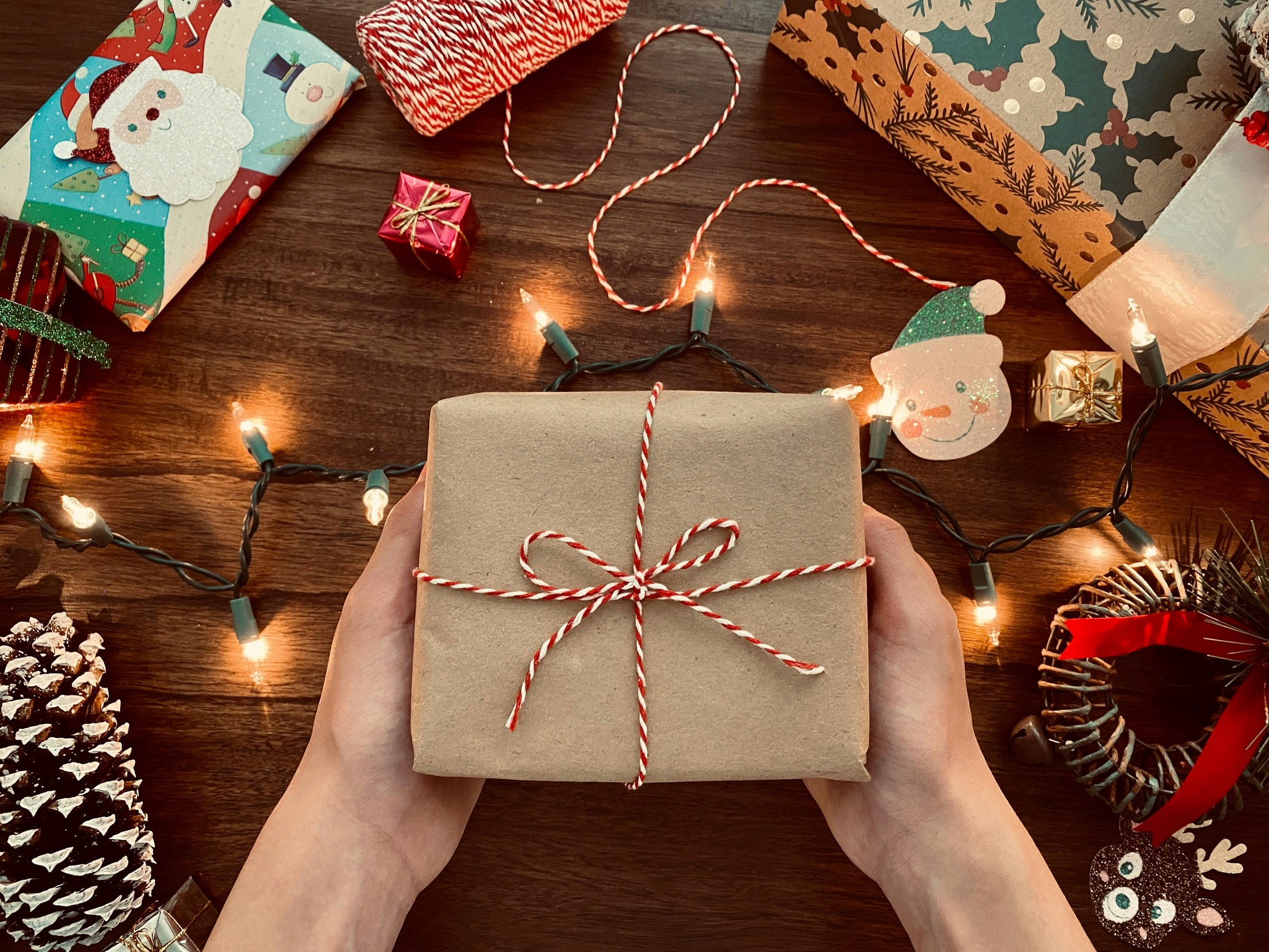A person holding a wrapped gift surrounded with holiday related items