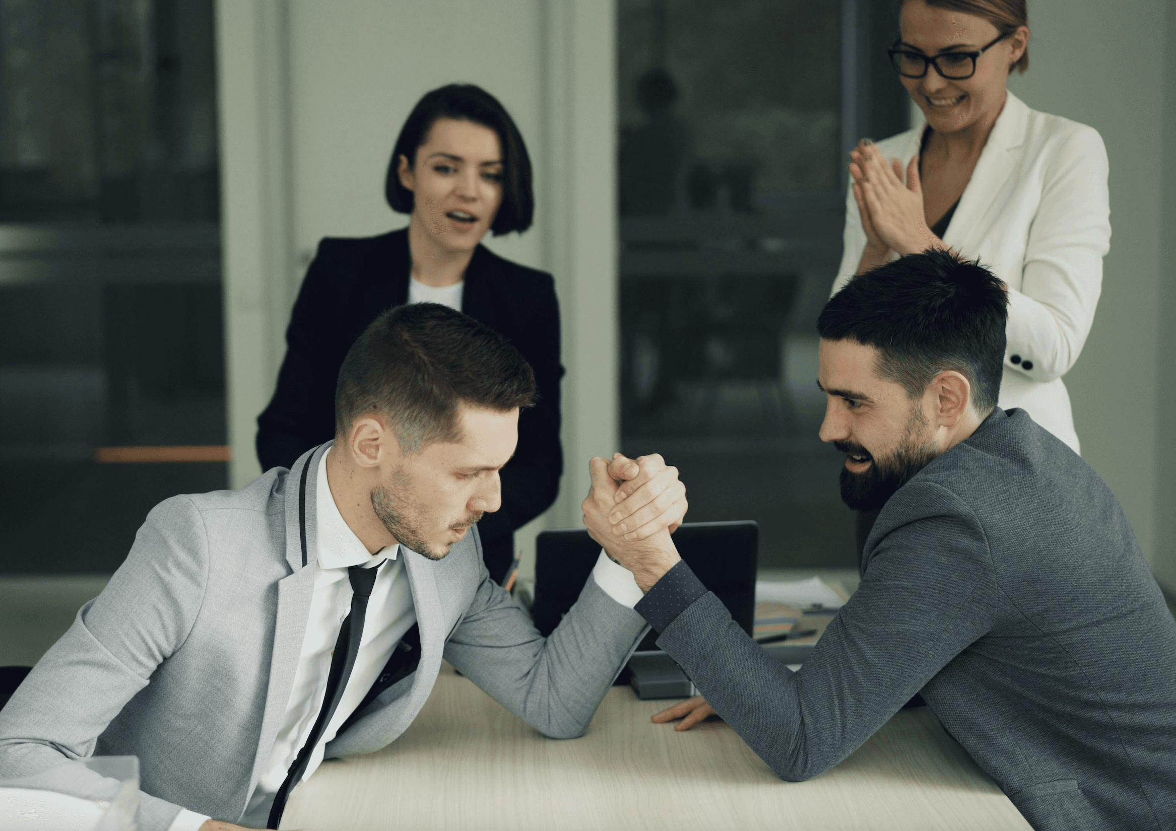 Two businessmen arm wrestling while colleagues watch