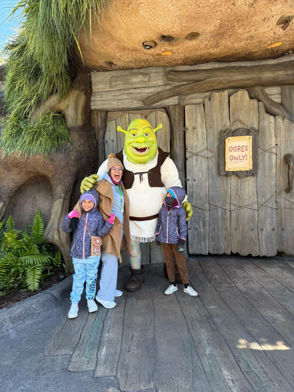 Foto de uma mãe segurando uma criança em um ambiente temático, representando viagens em família possíveis com pontos, milhas e compras bonificadas.