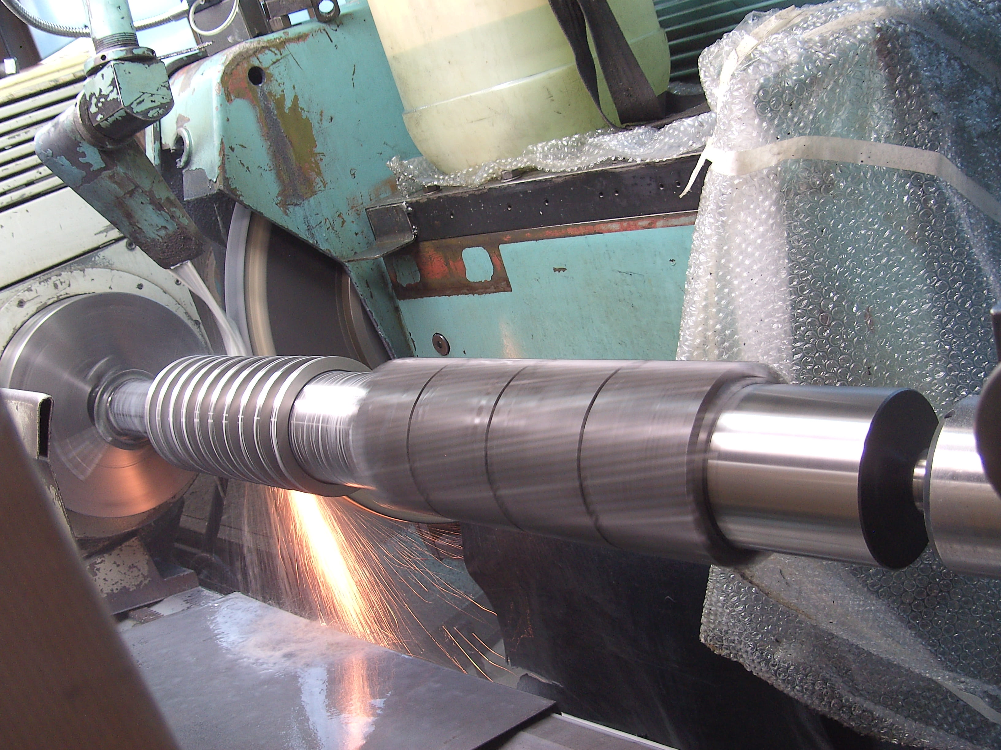 Rondslijpen van een as op een slijpmachine in de machinefabriek van Plasma Service
