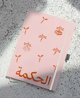 Carnet de notes rose avec un motif végétal orange et une typographie contemporaine arabe 
