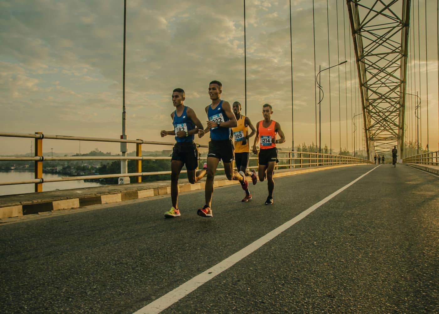 Physical impact of running - Four men racing across a bridge