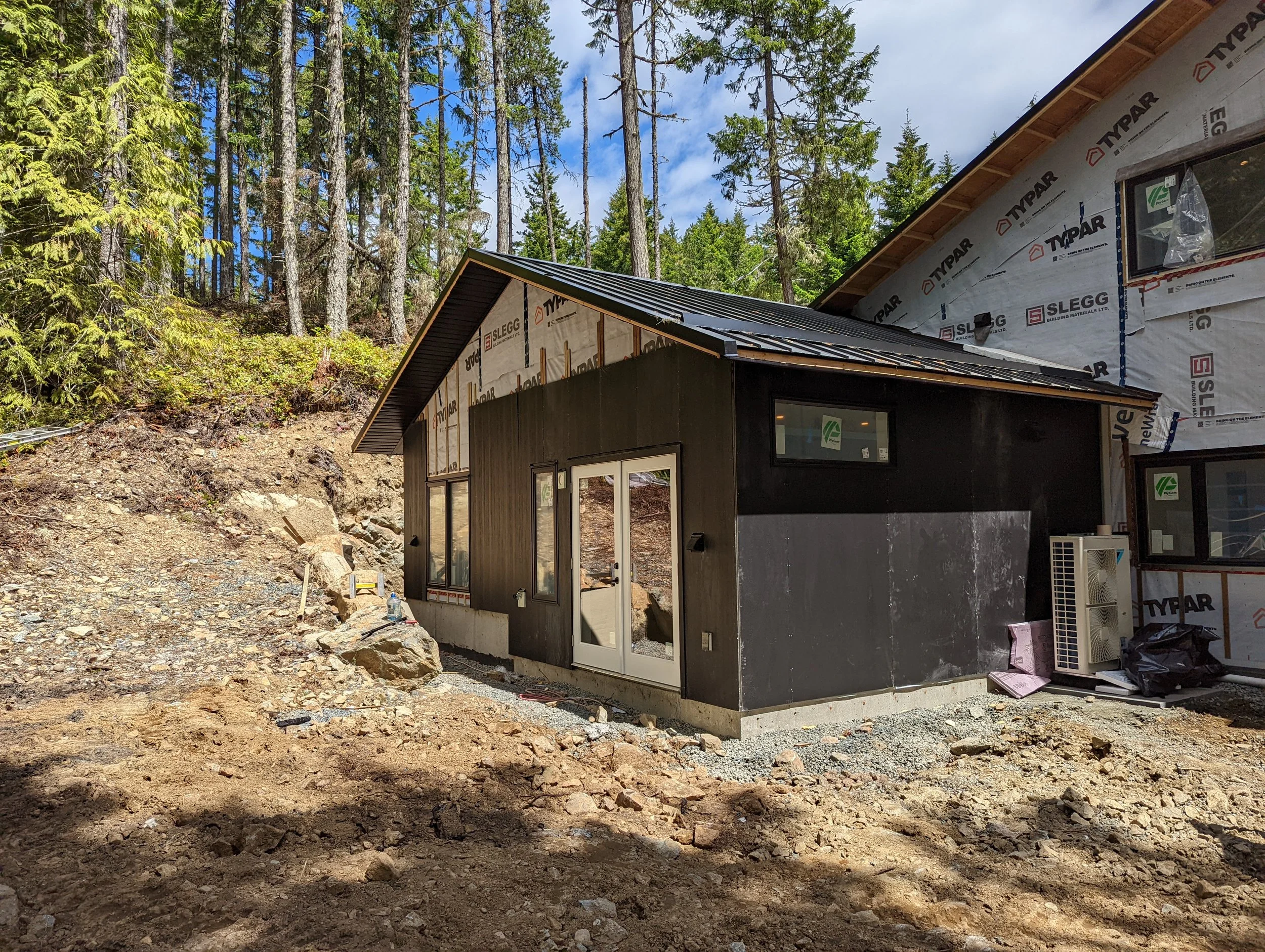 Modern two-story home with large glass windows, warmly lit interiors, and a balcony. Surrounded by trees and a manicured lawn at dusk. Cozy ambiance.