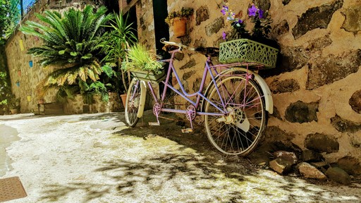 a purple bike parked next to a stone wall in France, illustrating enjoying France