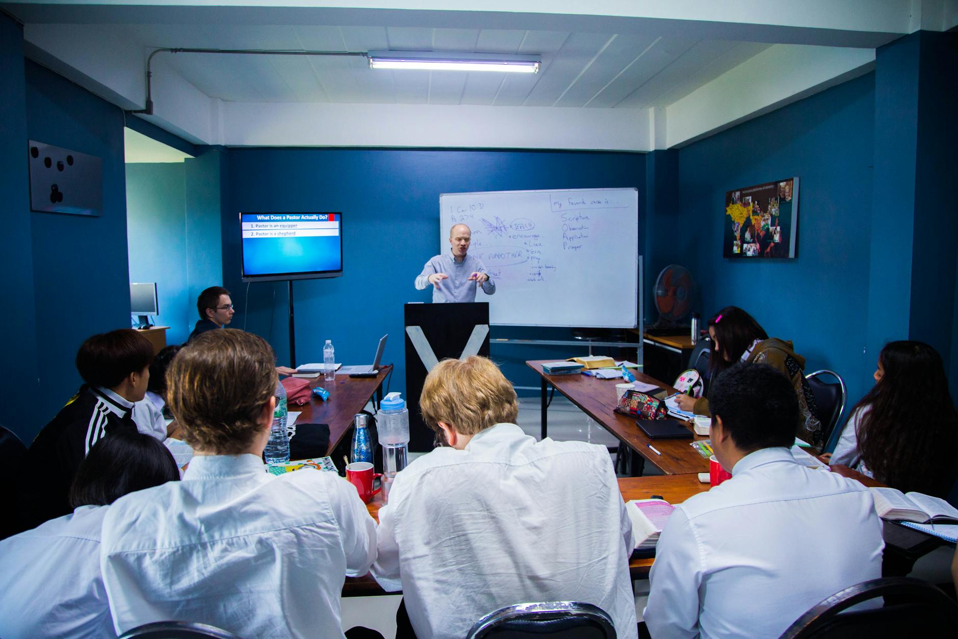 A group of diverse educators collaborating around a table during a hands-on workshop in a sunlit classroom.