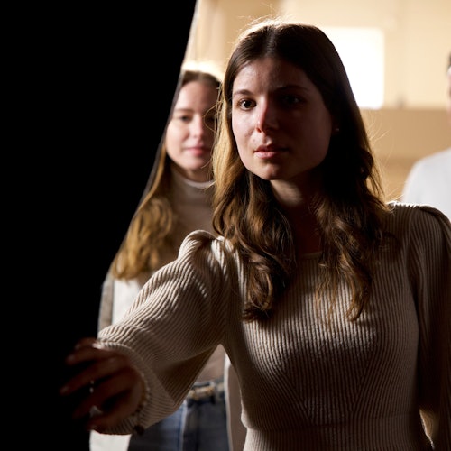 A woman gazes intently into a dark room.