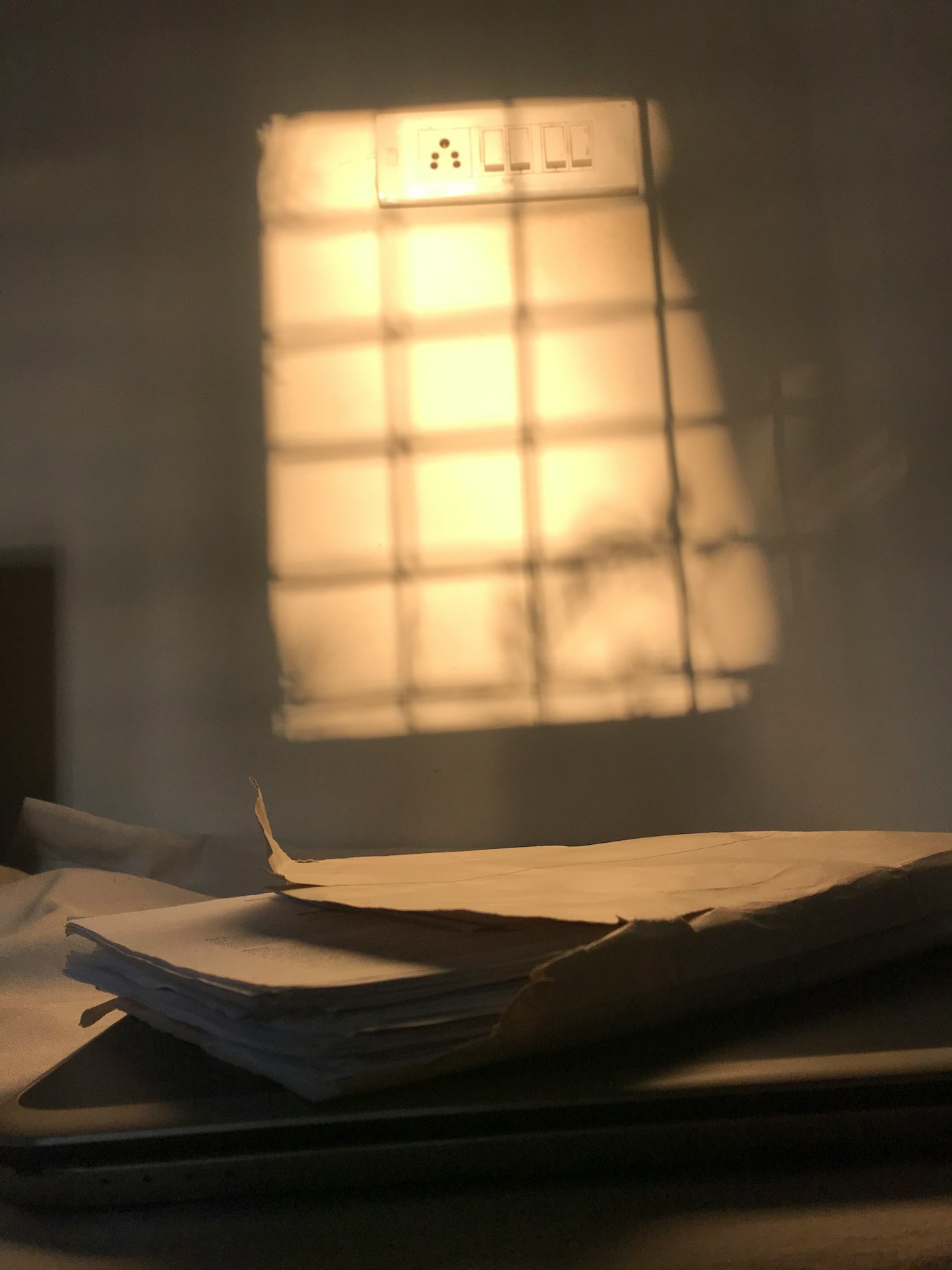 A stack of old papers under a window-shaped patch of light
