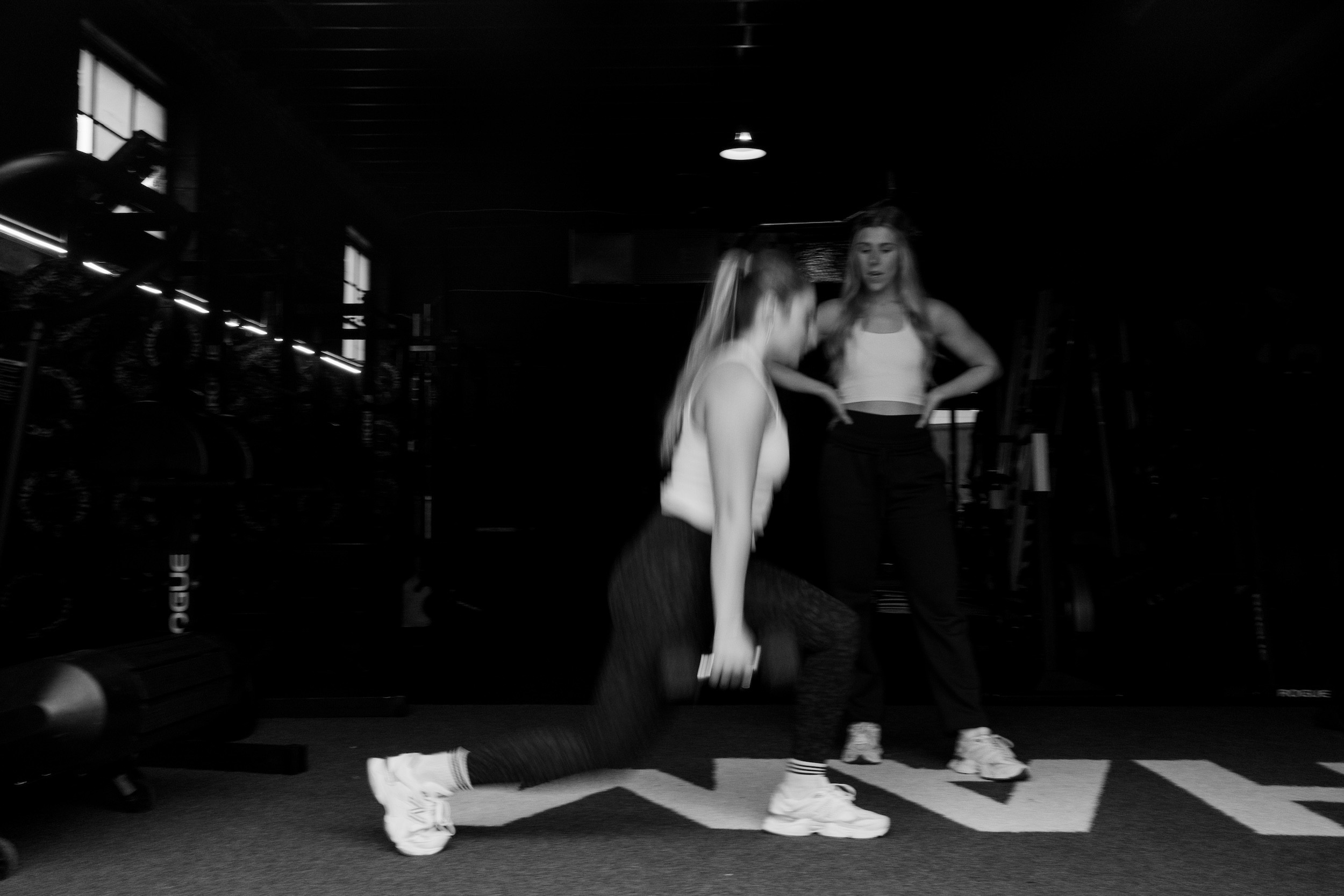 Female fitness coach watching a client do lunges