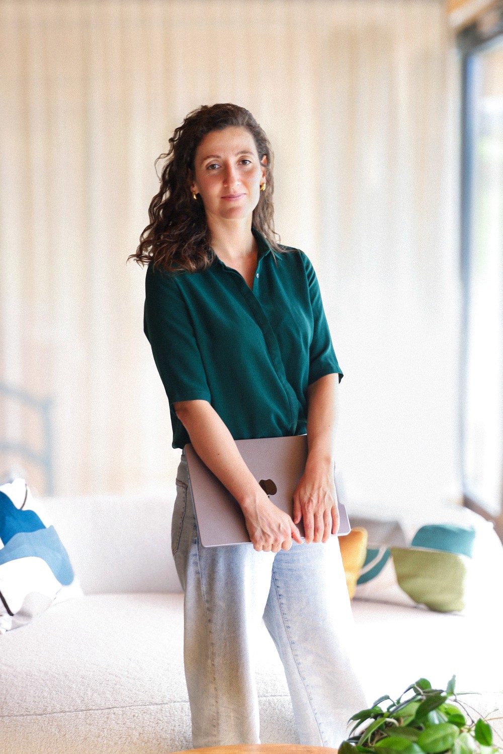 Carina präsentiert sich mit professionellen Auftreten und Laptop in einem hellen Raum.