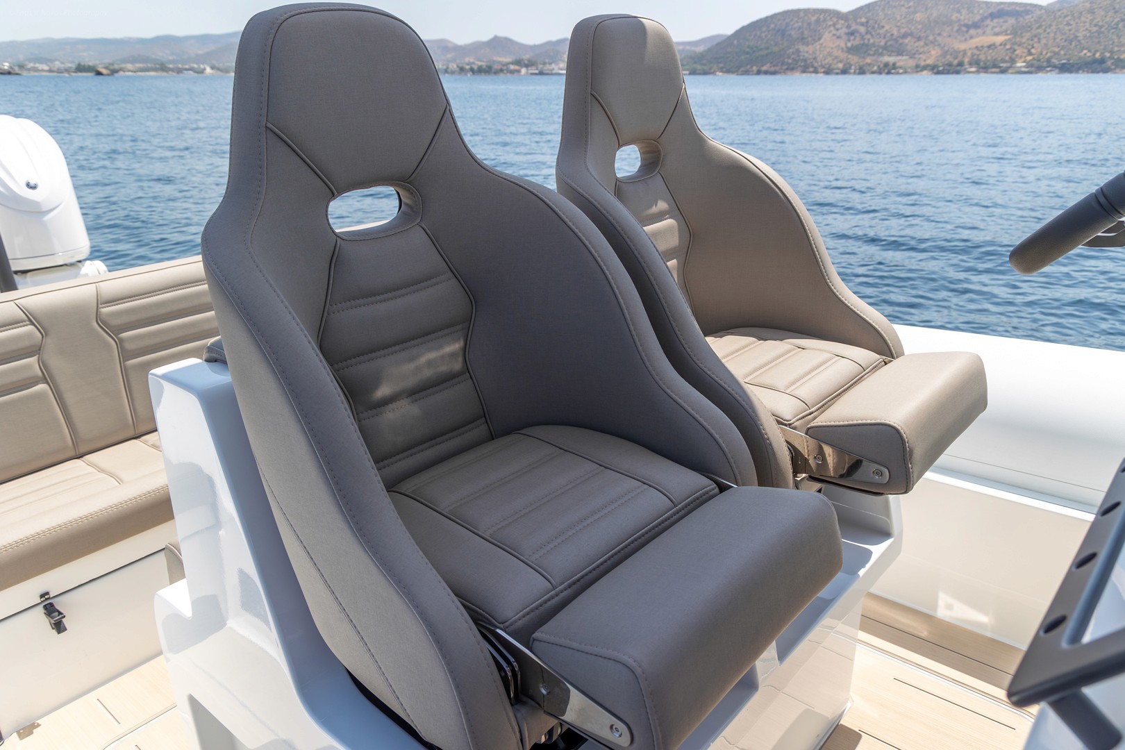 White Rock 36 yacht bow seating area with grey upholstery and helm station, anchored in calm blue waters near Greek islands.