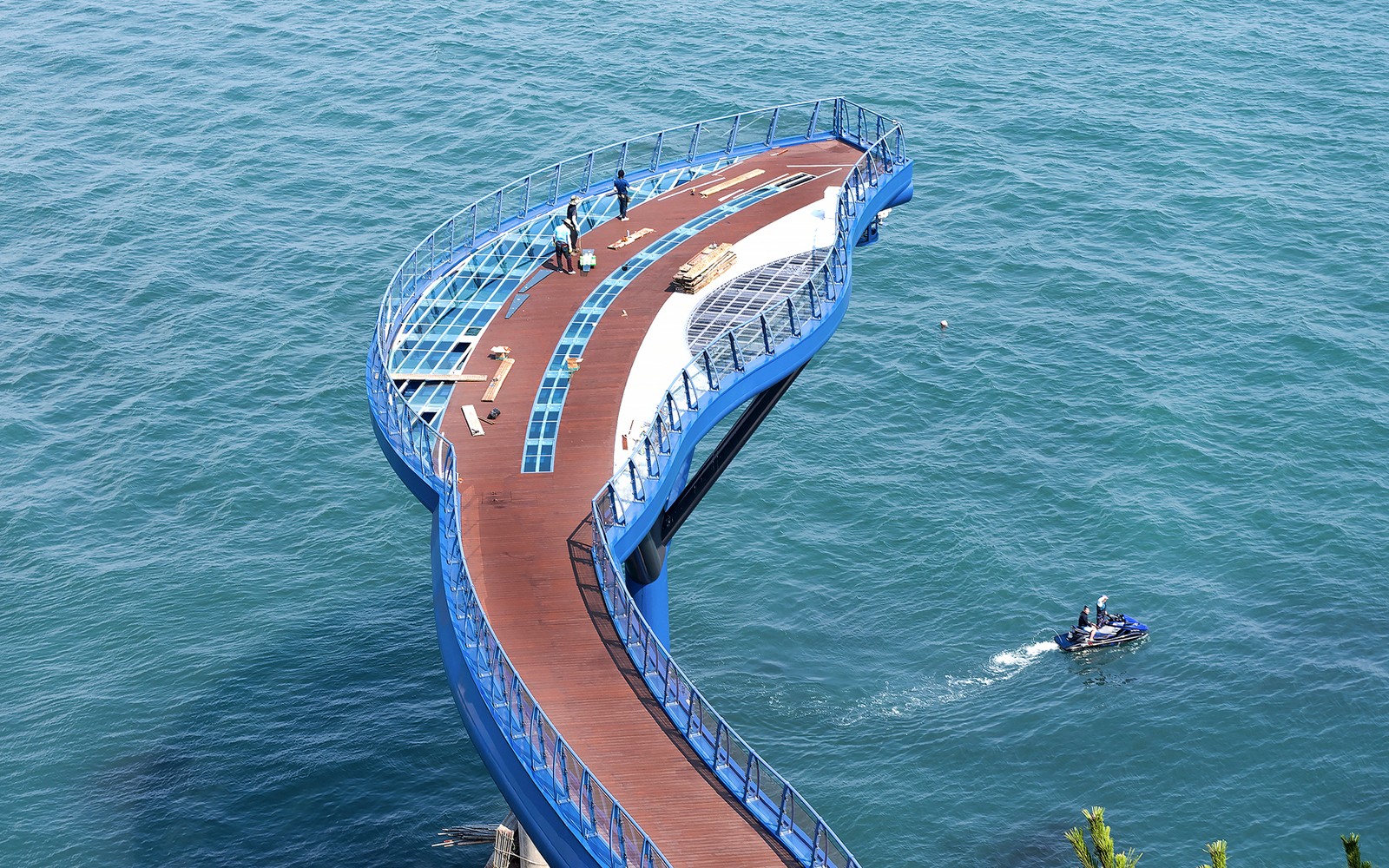 Blueline Park Sky Kapsel Plattform über dem Ozean in Busan, Südkorea, mit Menschen und Jetski in der Nähe.