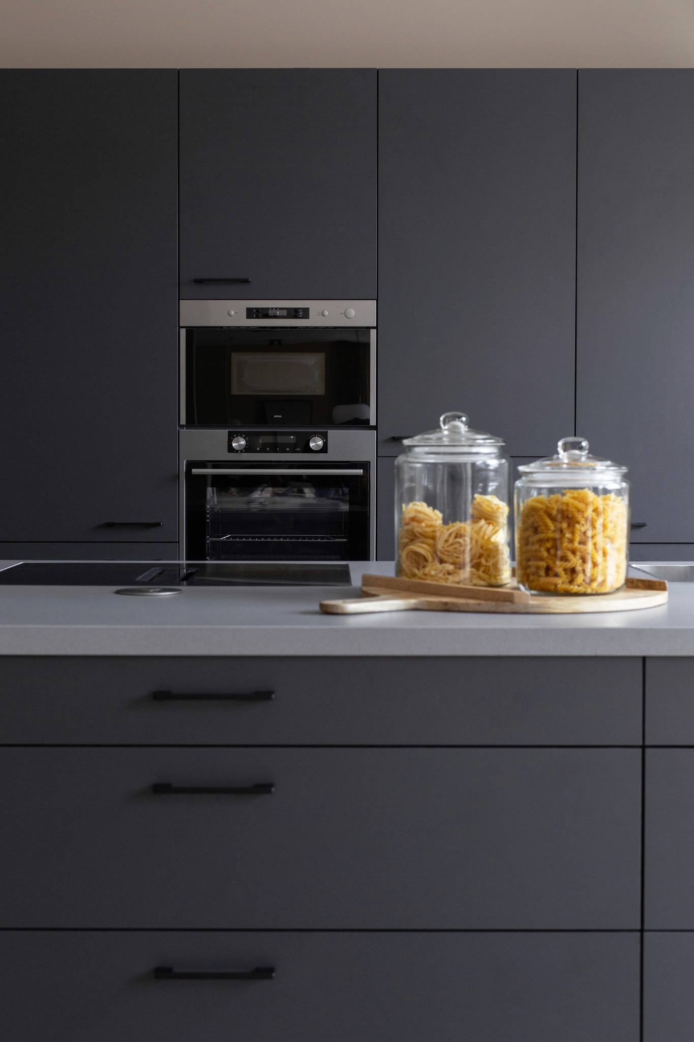 donker grijze keuken met eiland en hoge kastenwand