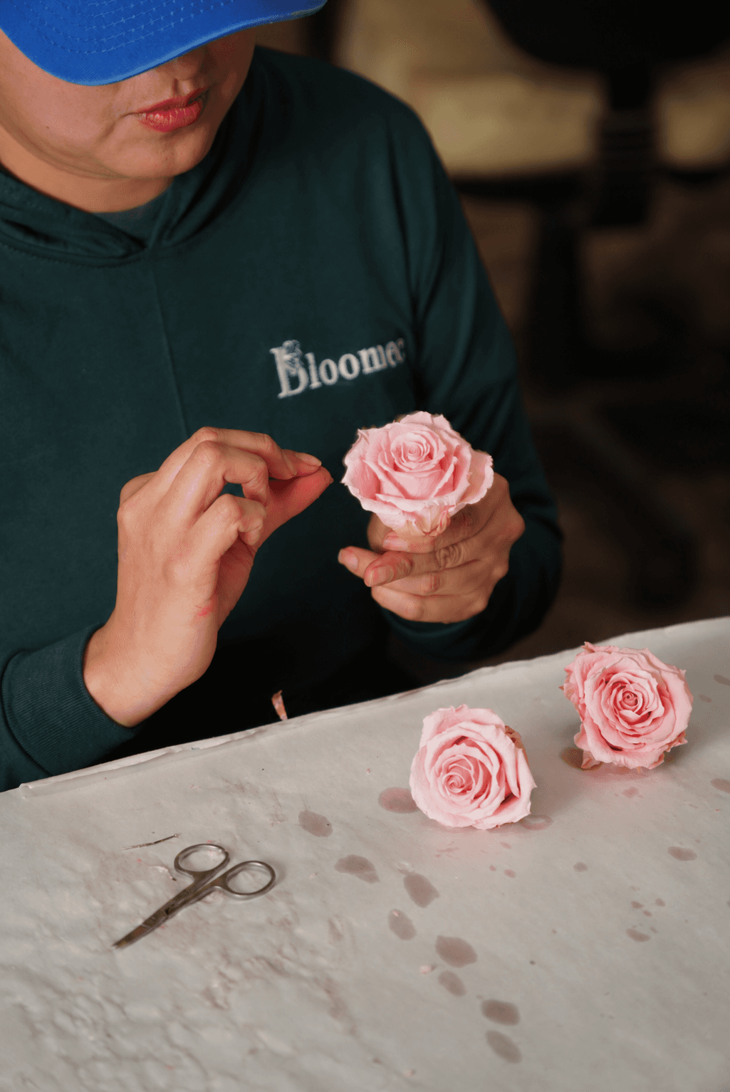 BLOOMEC artisan carefully shaping a pink rose by hand.