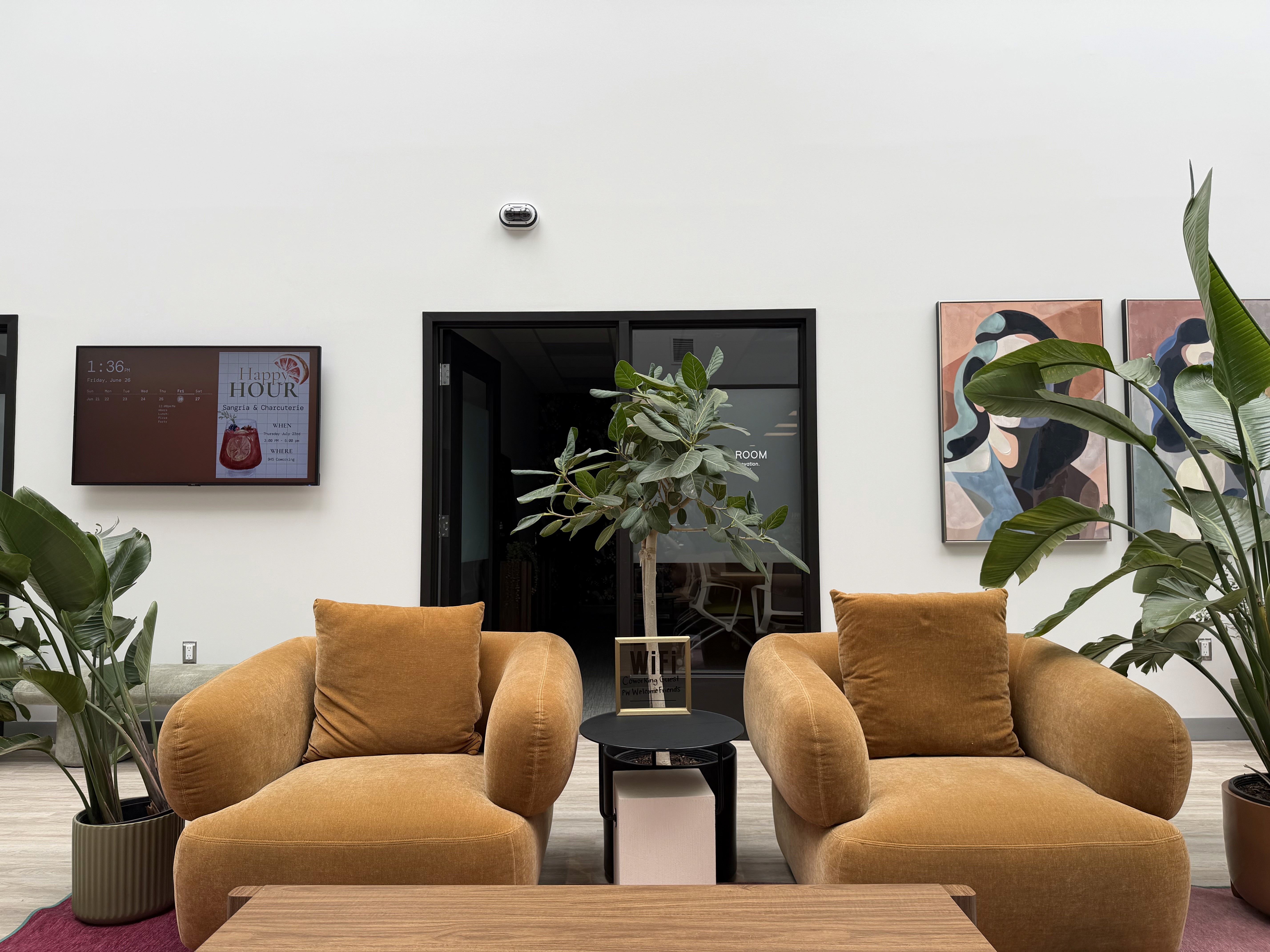Bright open office space with pink walls, abstract wall art, and rows of workstations with monitors