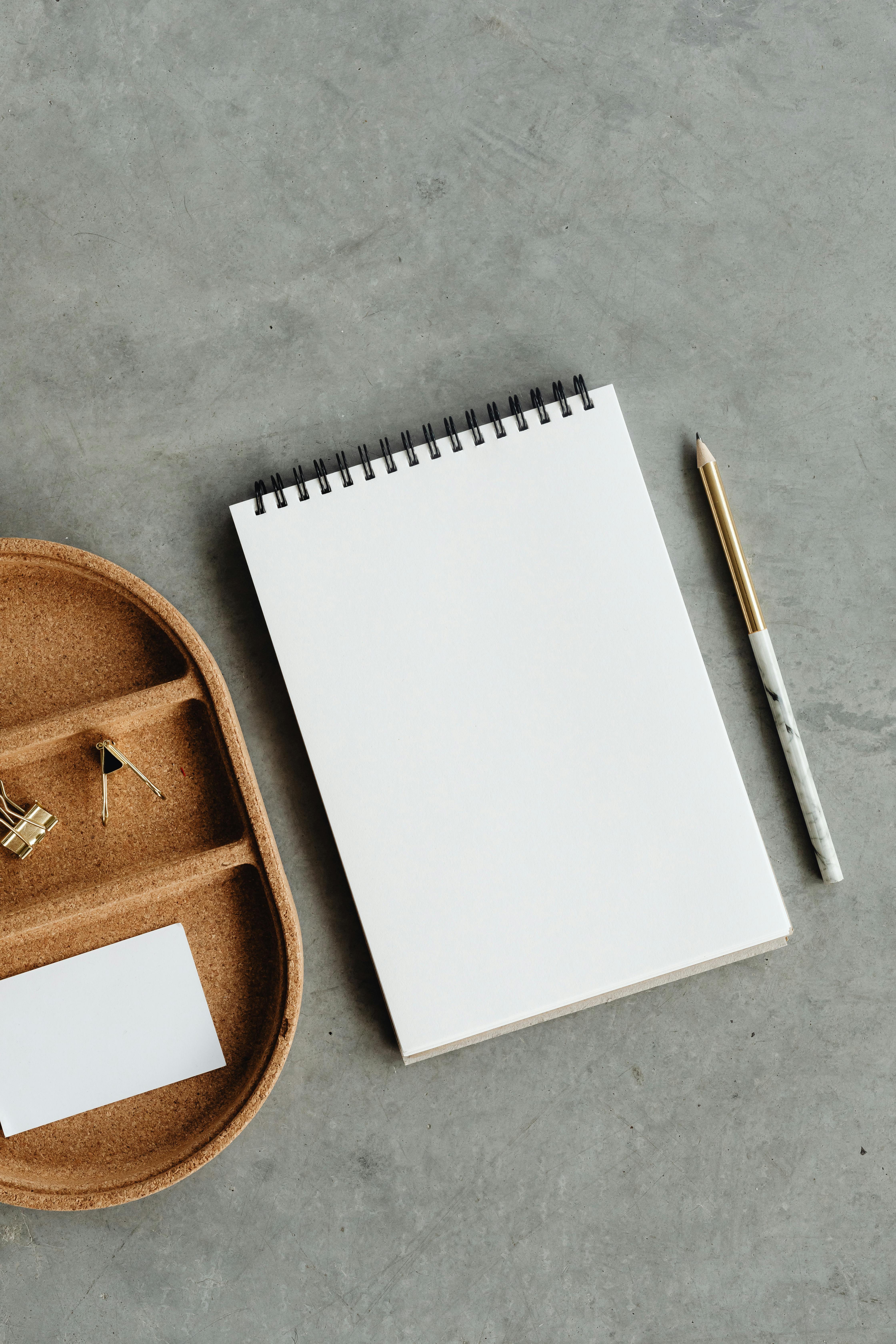 Blank notebook, pencil, and table surface.