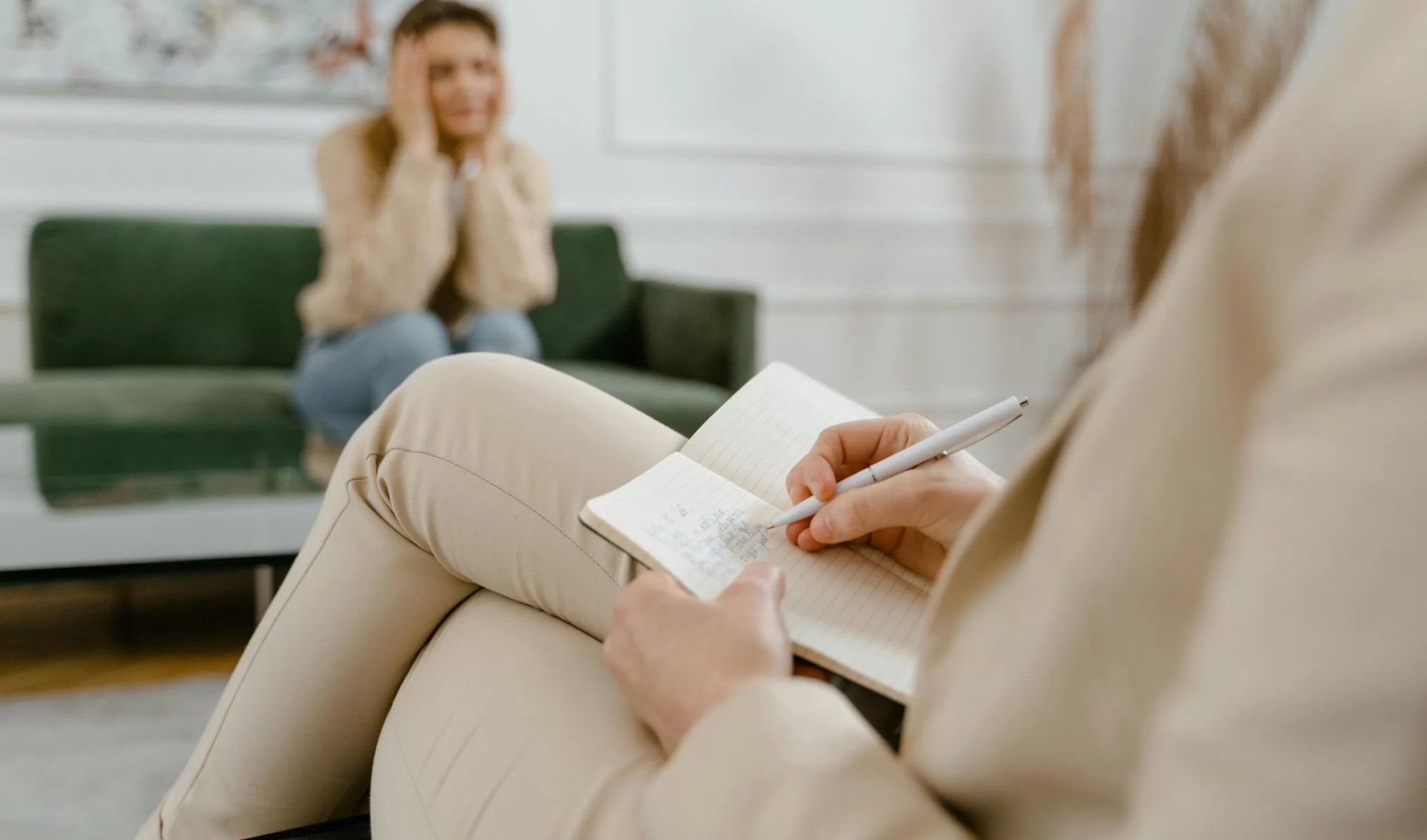 Enfoque en la psicoterapia individual, con la terapeuta tomando notas mientras escucha.