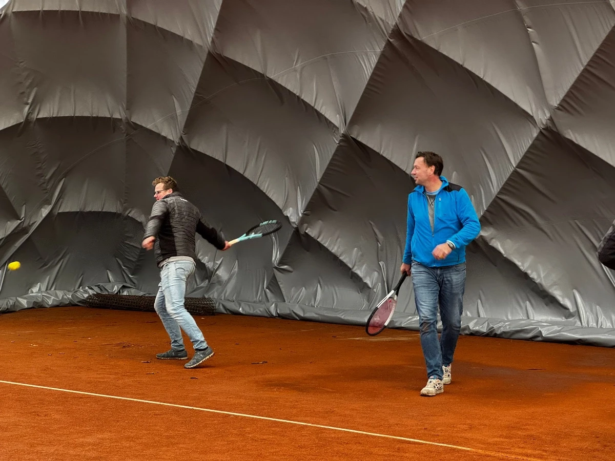 person in black shorts holding green tennis racket