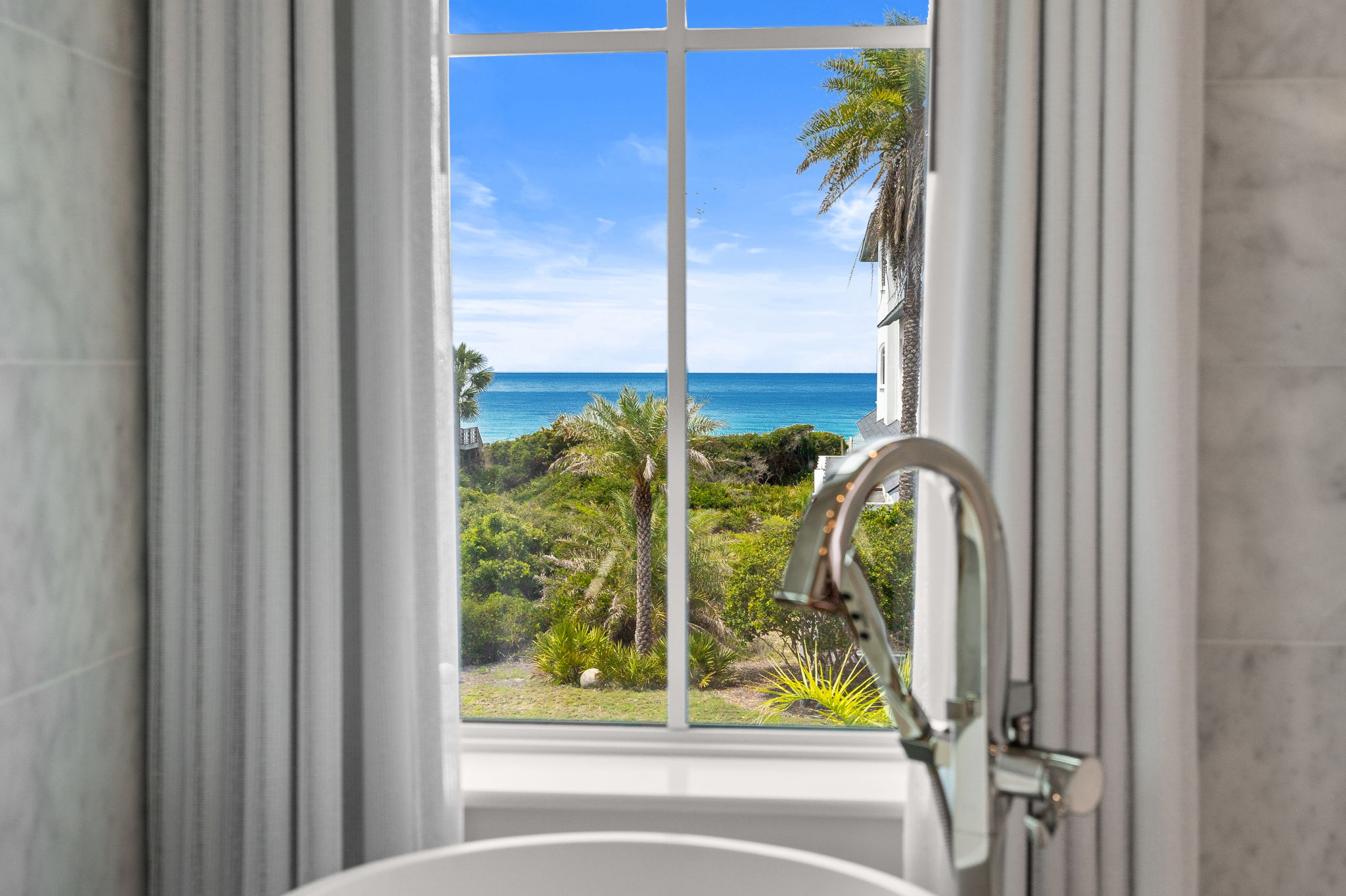 Freestanding tub beside a window overlooking the Gulf in an Alys Beach, FL vacation rental