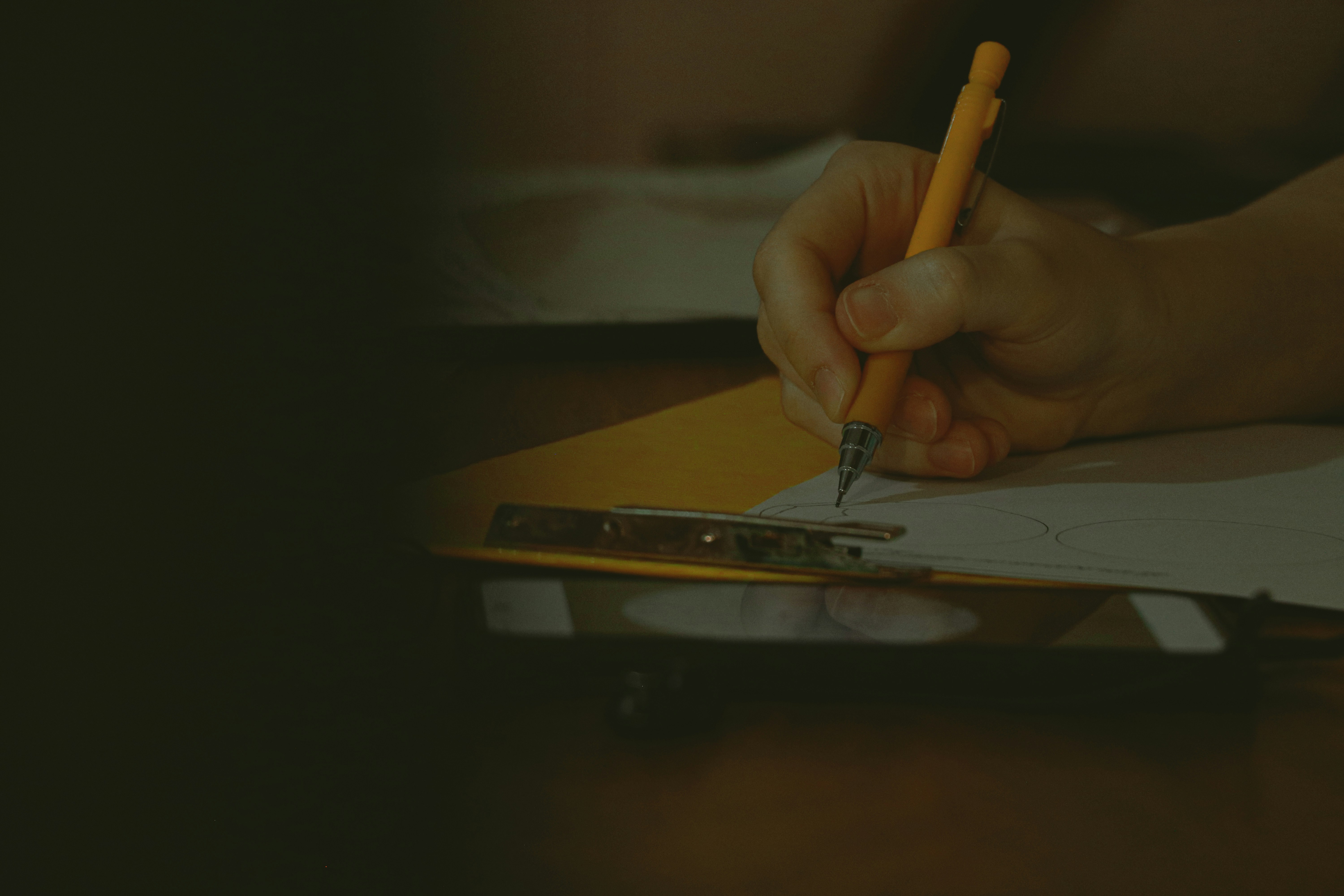 A hand is writing on a clipboard.
